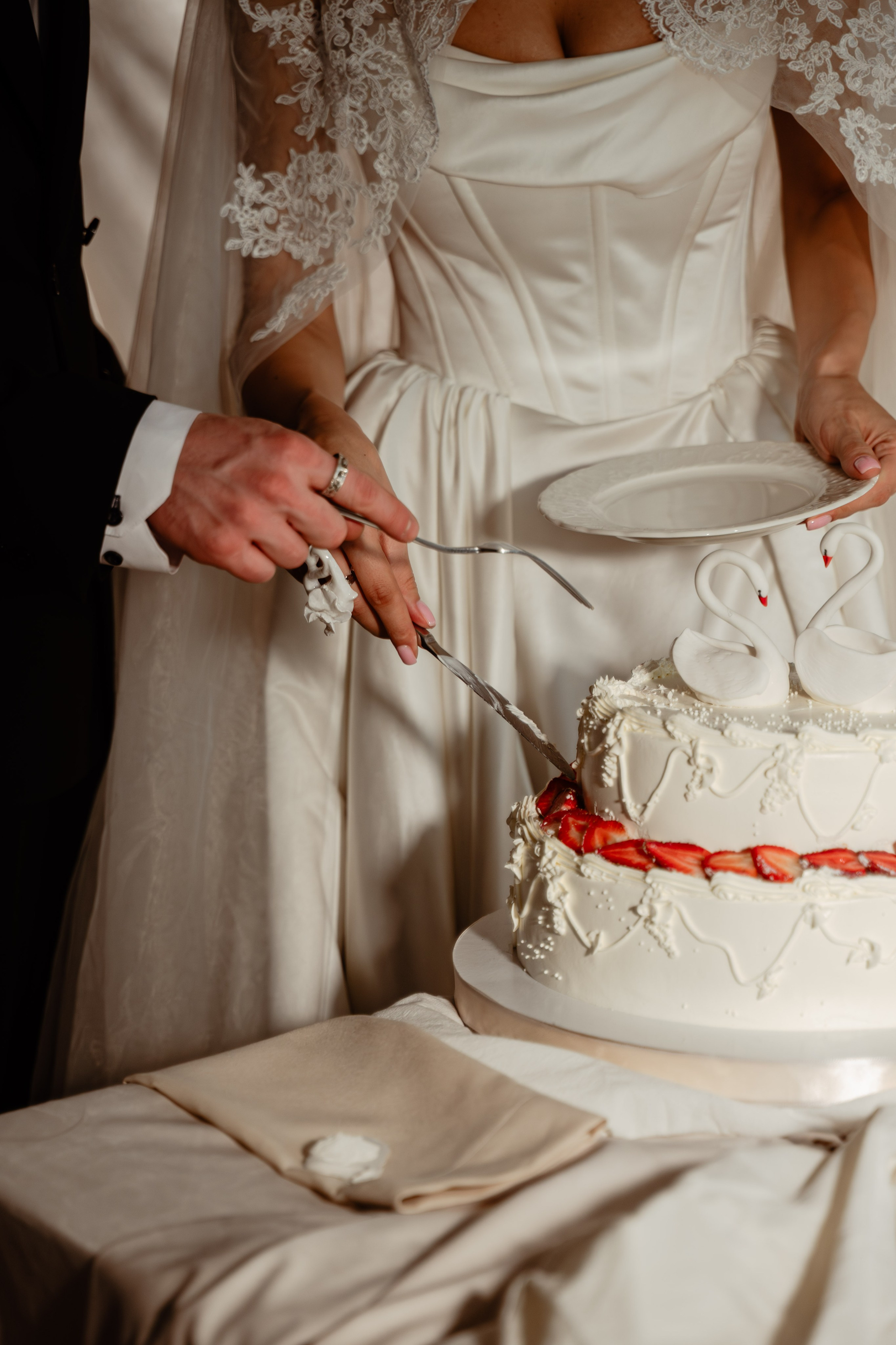 Руки жениха и невесты держат нож на свадебном торте — символический момент церемонии