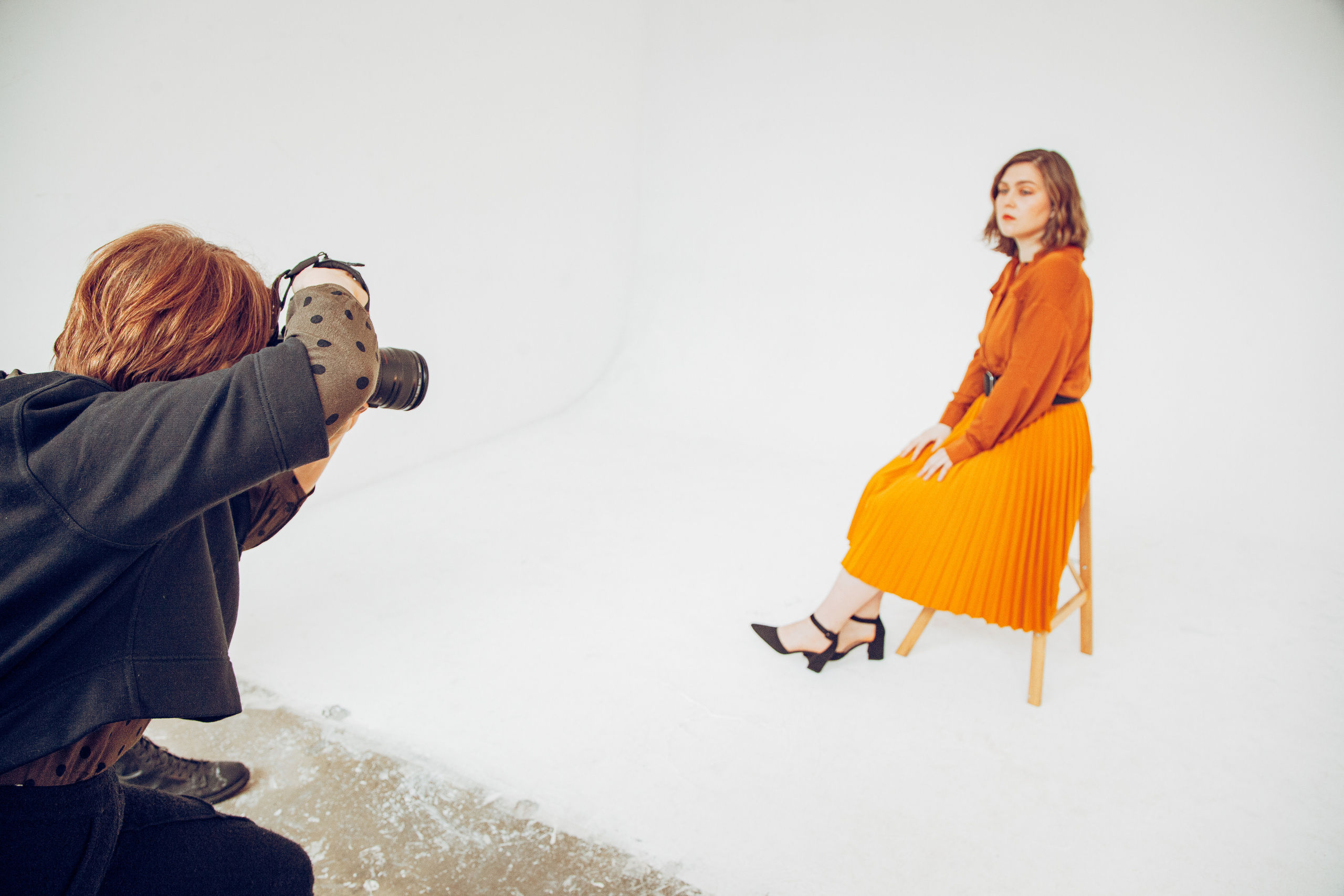 Фотограф снимет девушку в желтой юбке, сидящую на стуле