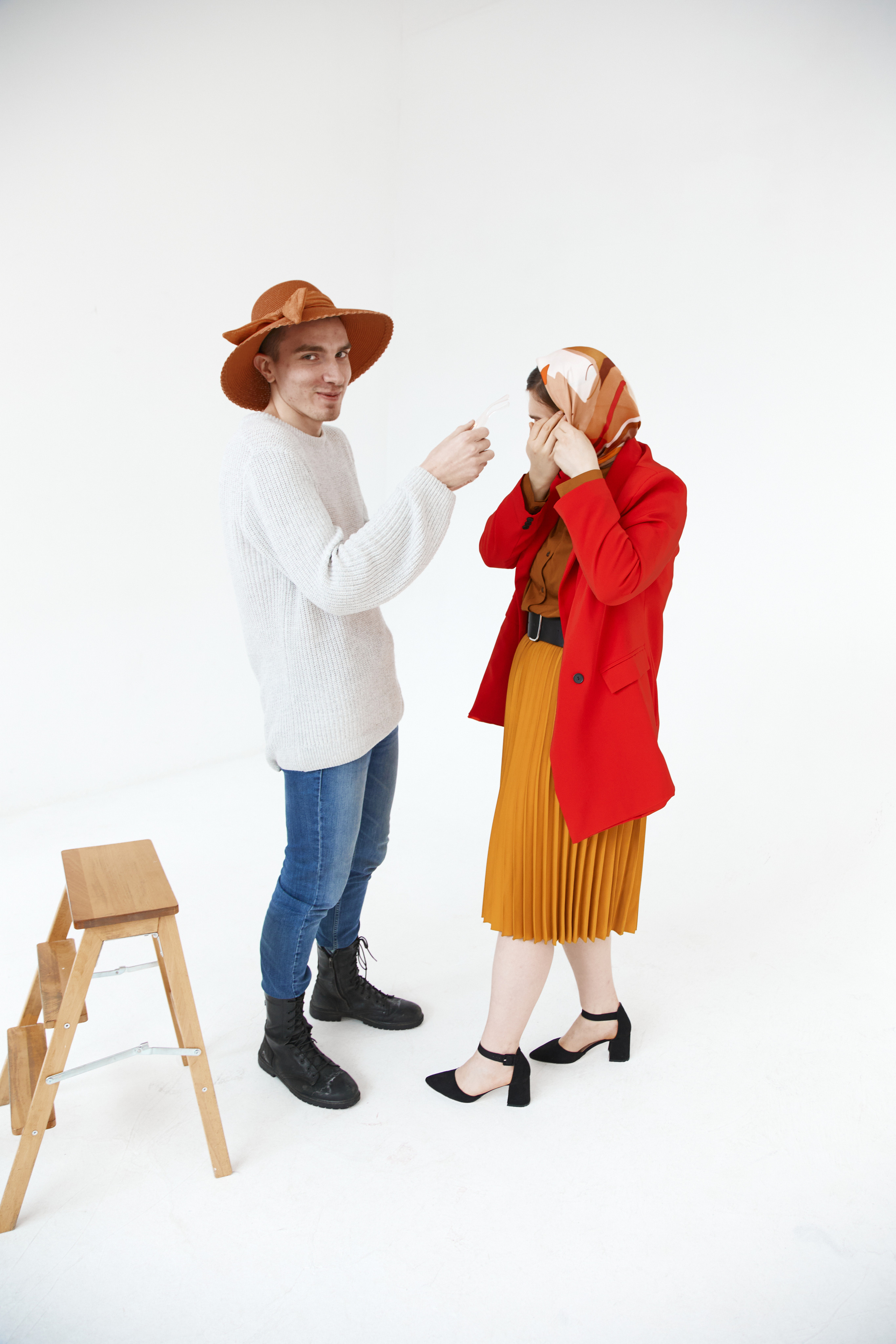 Стилист в шляпе поправляет элементы одежды модели