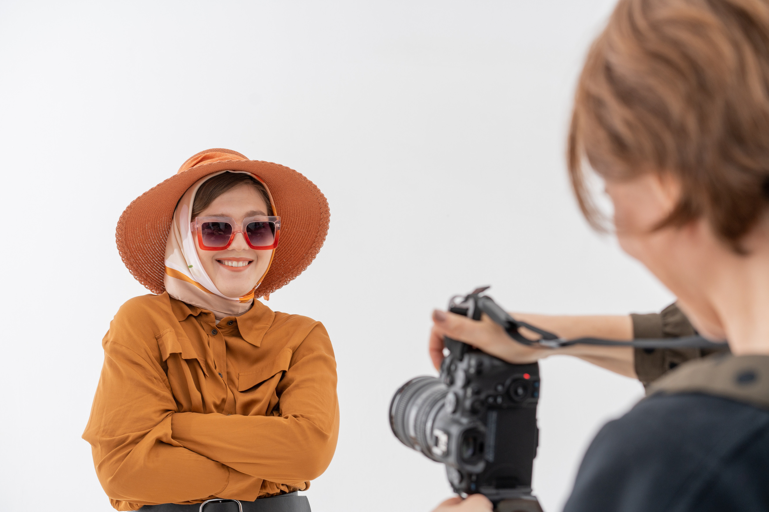 Девушка в шляпе очках позирует фотографу