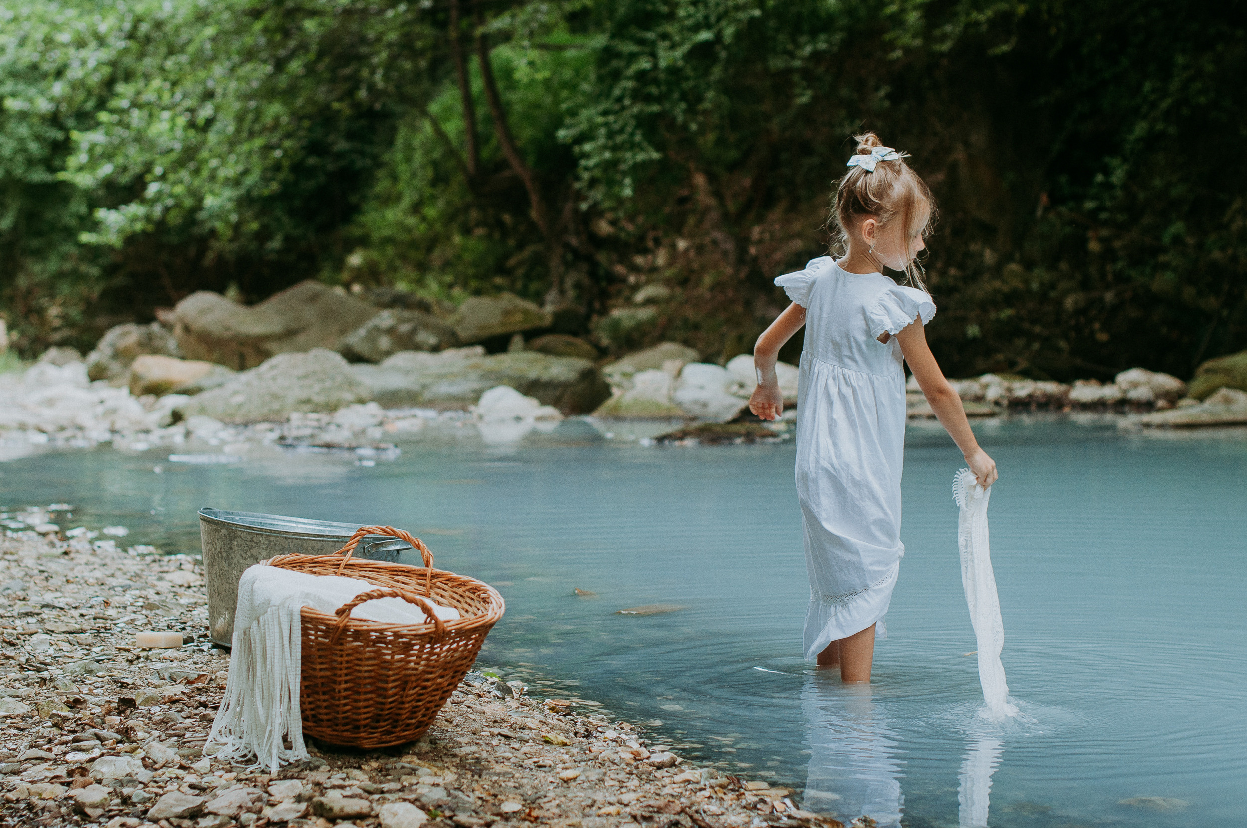 Девочка в белоснежном платье стирает вещи в реке Агура в Сочи