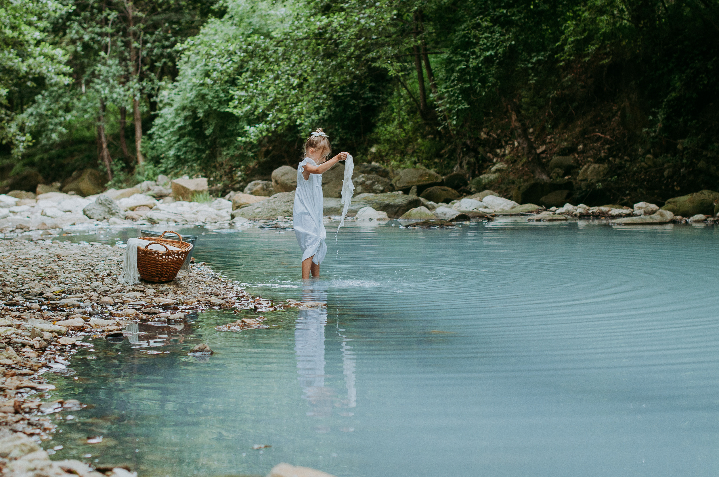 Девочка в белоснежном платье стирает вещи в реке Агура в Сочи