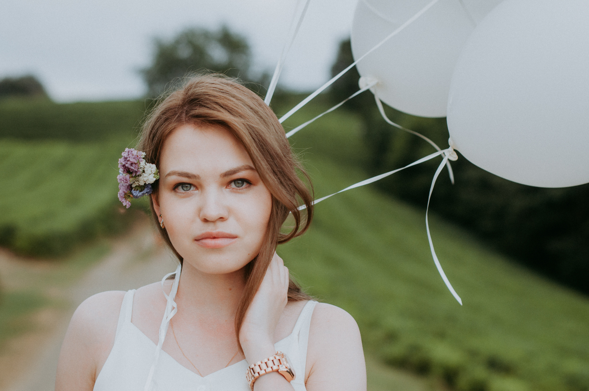 Красивая шатенка в белом с белыми воздушными шарами на чайных плантациях в Сочи