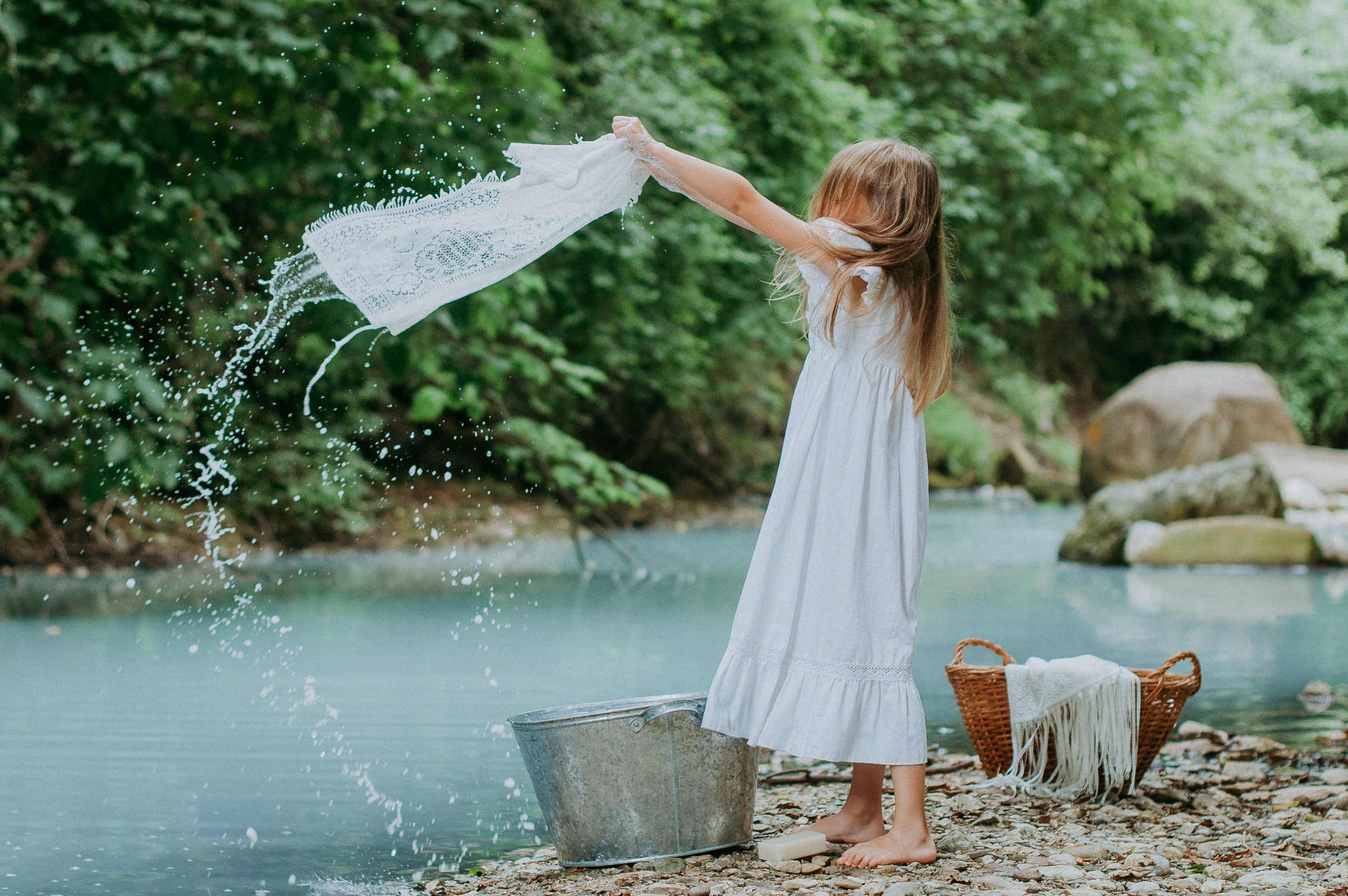 Девочка в белоснежном платье стирает вещи в реке Агура в Сочи