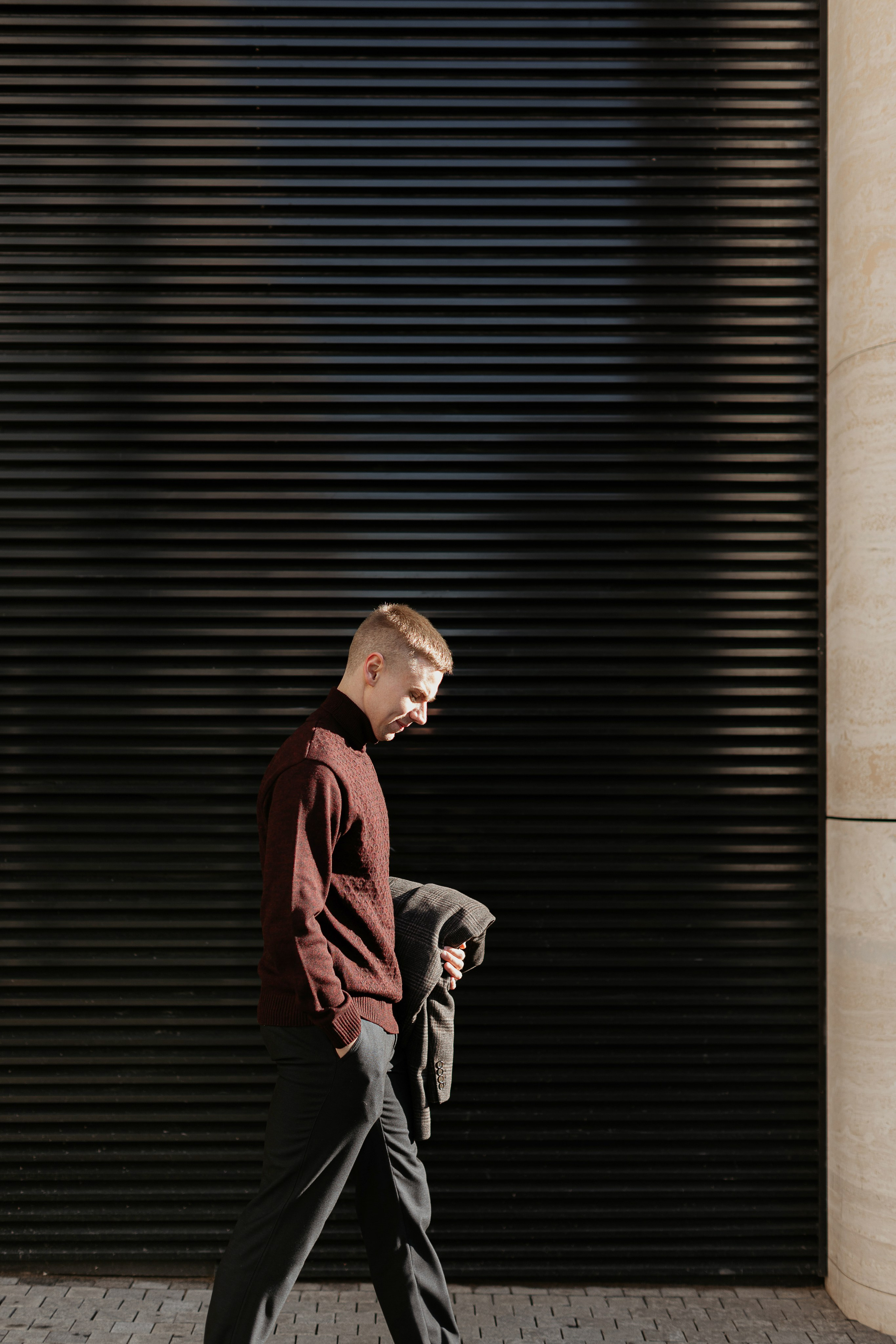 Мужчина в водолазке и брюках идет по улице