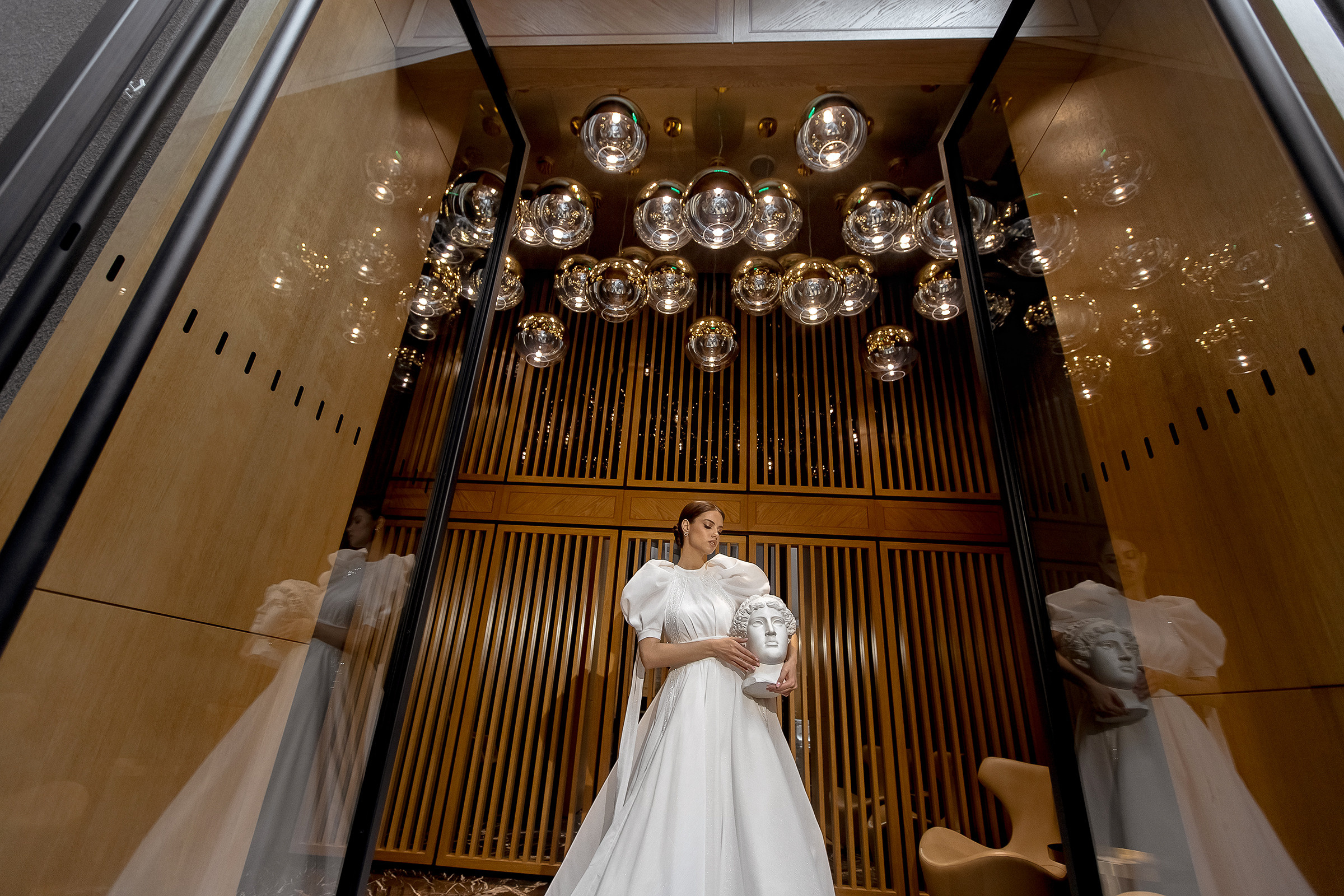 Свадебная фотосессия в отеле Gamma: невеста стоит на фоне красивых светильников