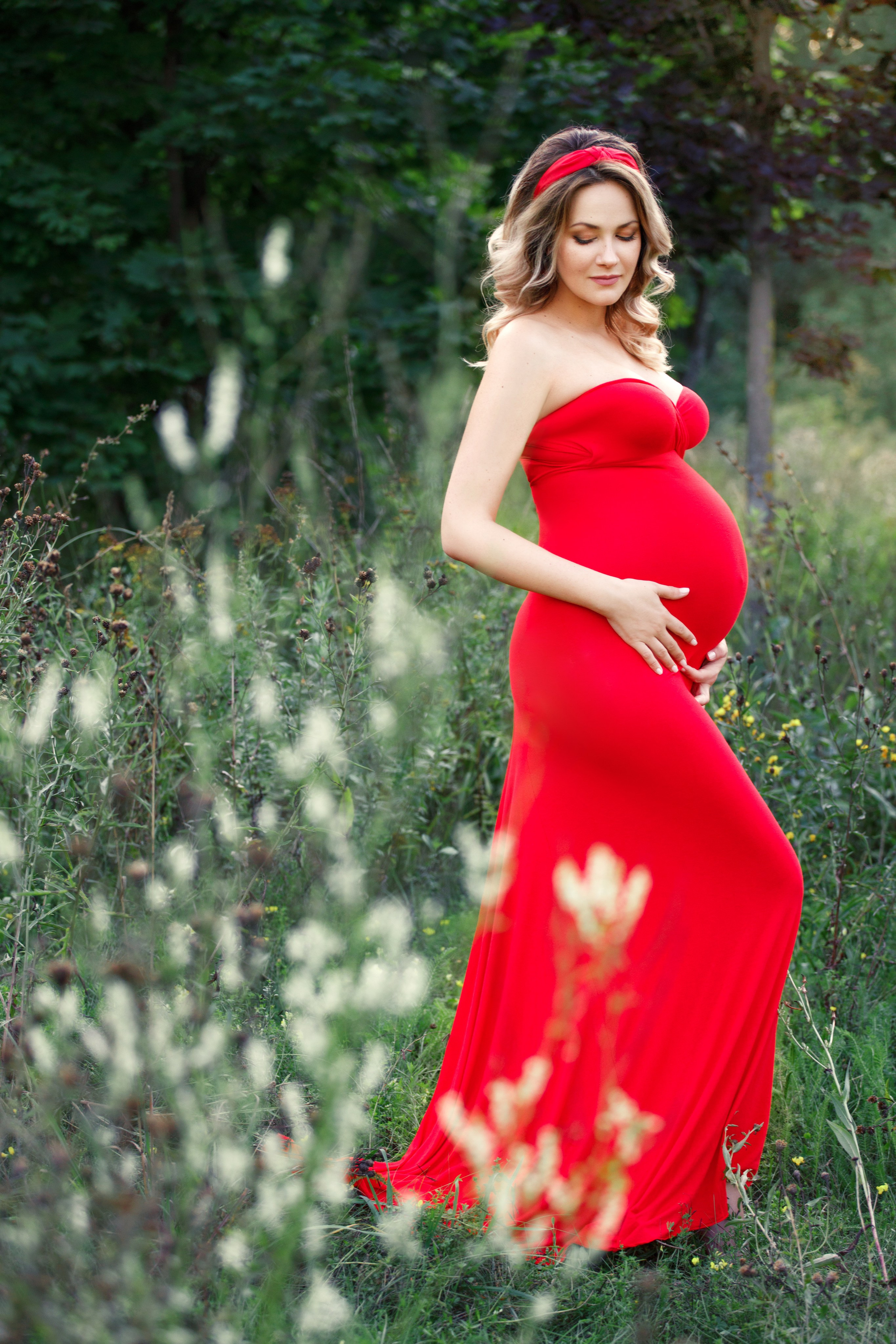 Беременная девушка фотографируется в парке