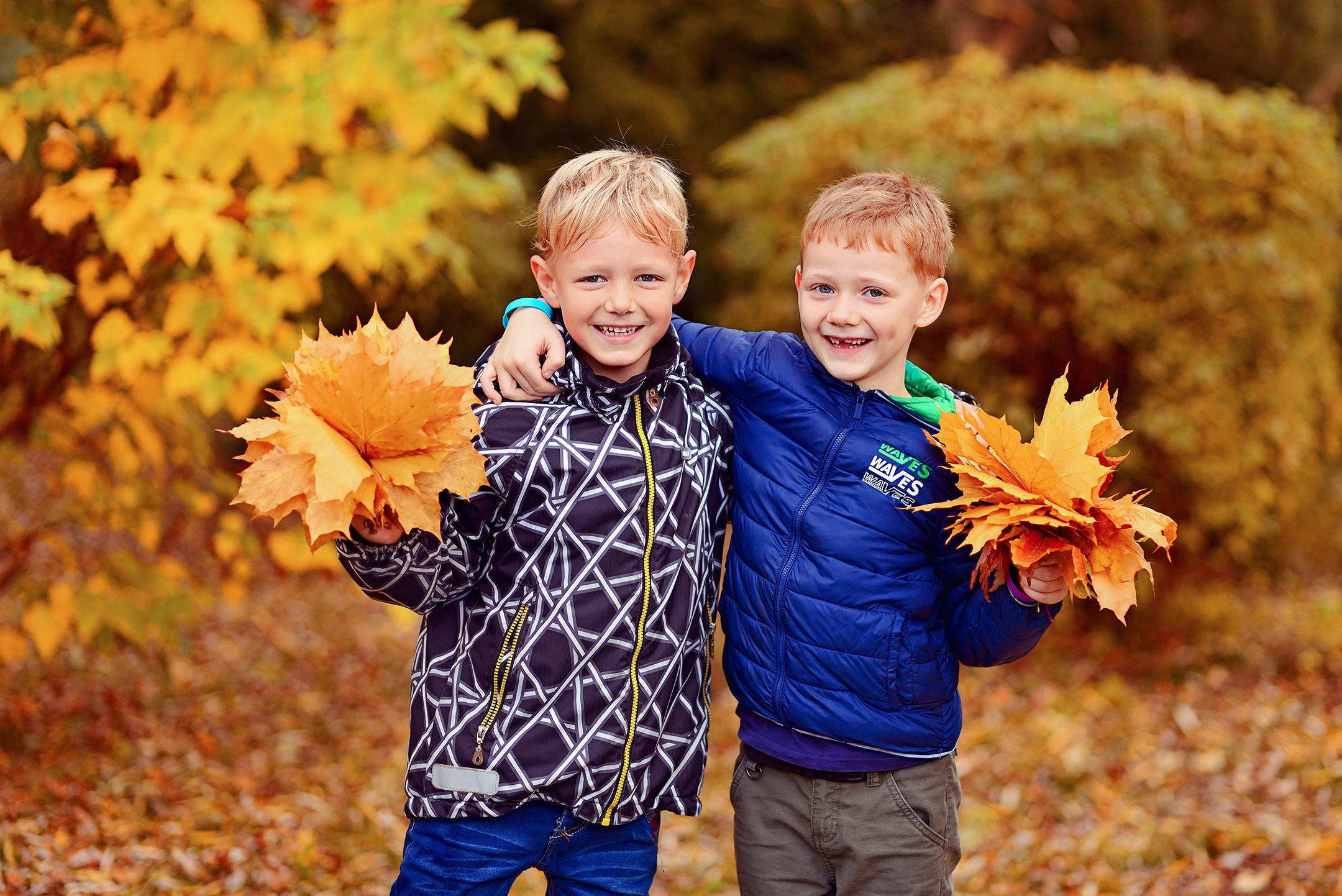 Двое мальчиков с осенними букетами на прогулке в детском саду.