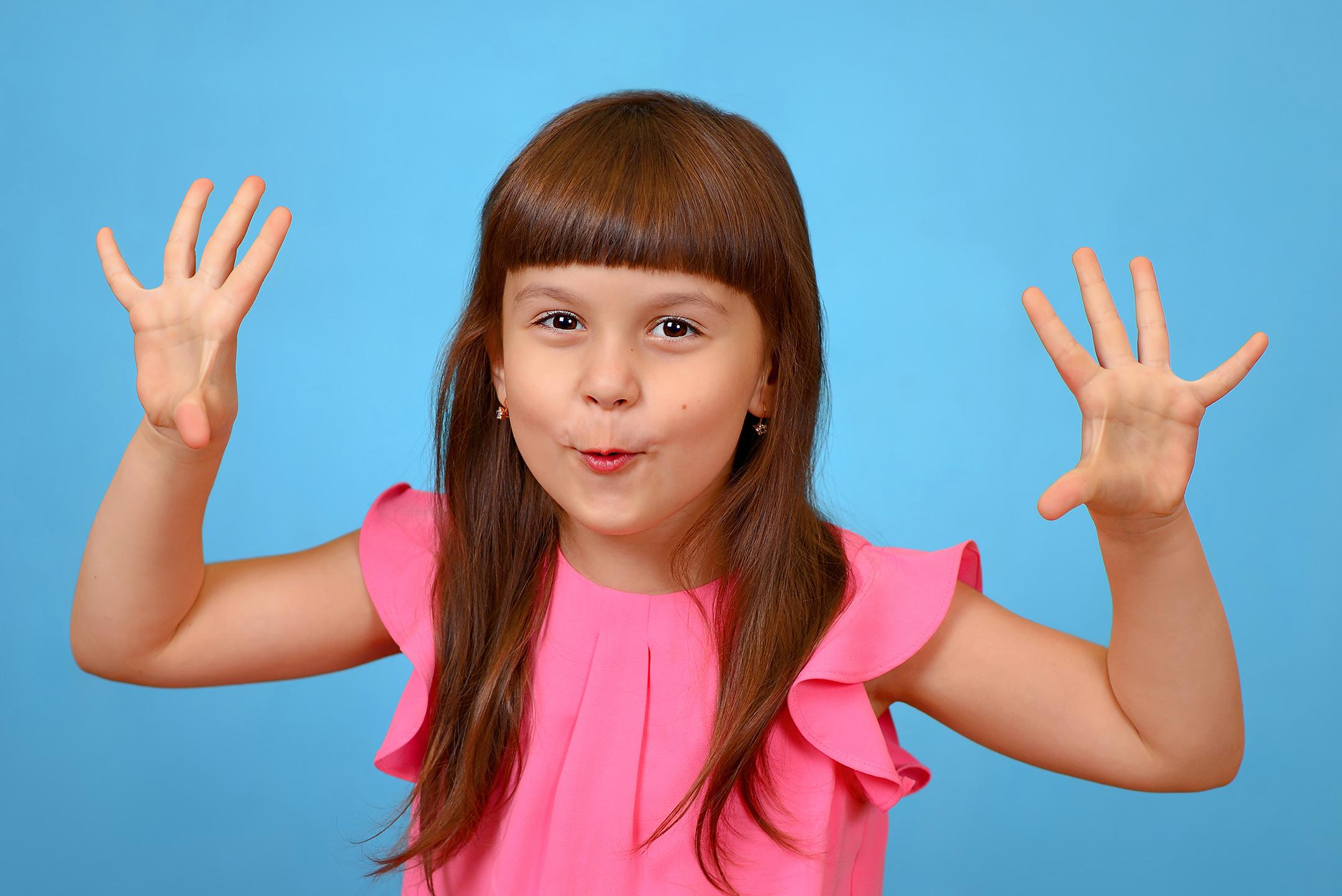 Игровой эмоциональный портрет девочки, выставившей вперёд руки, чтобы напугать фотографа.