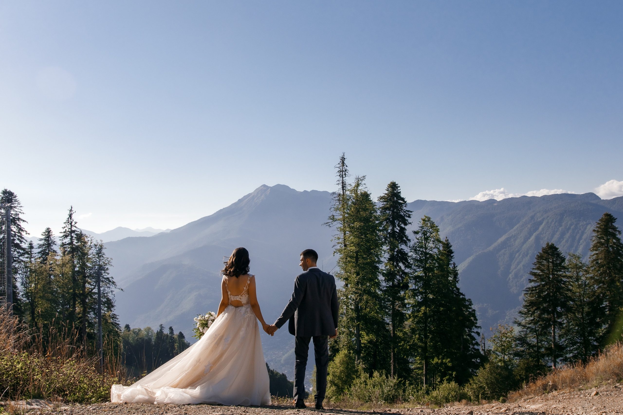 Невеста с букетом среди сосен в свадебной локации Поляны