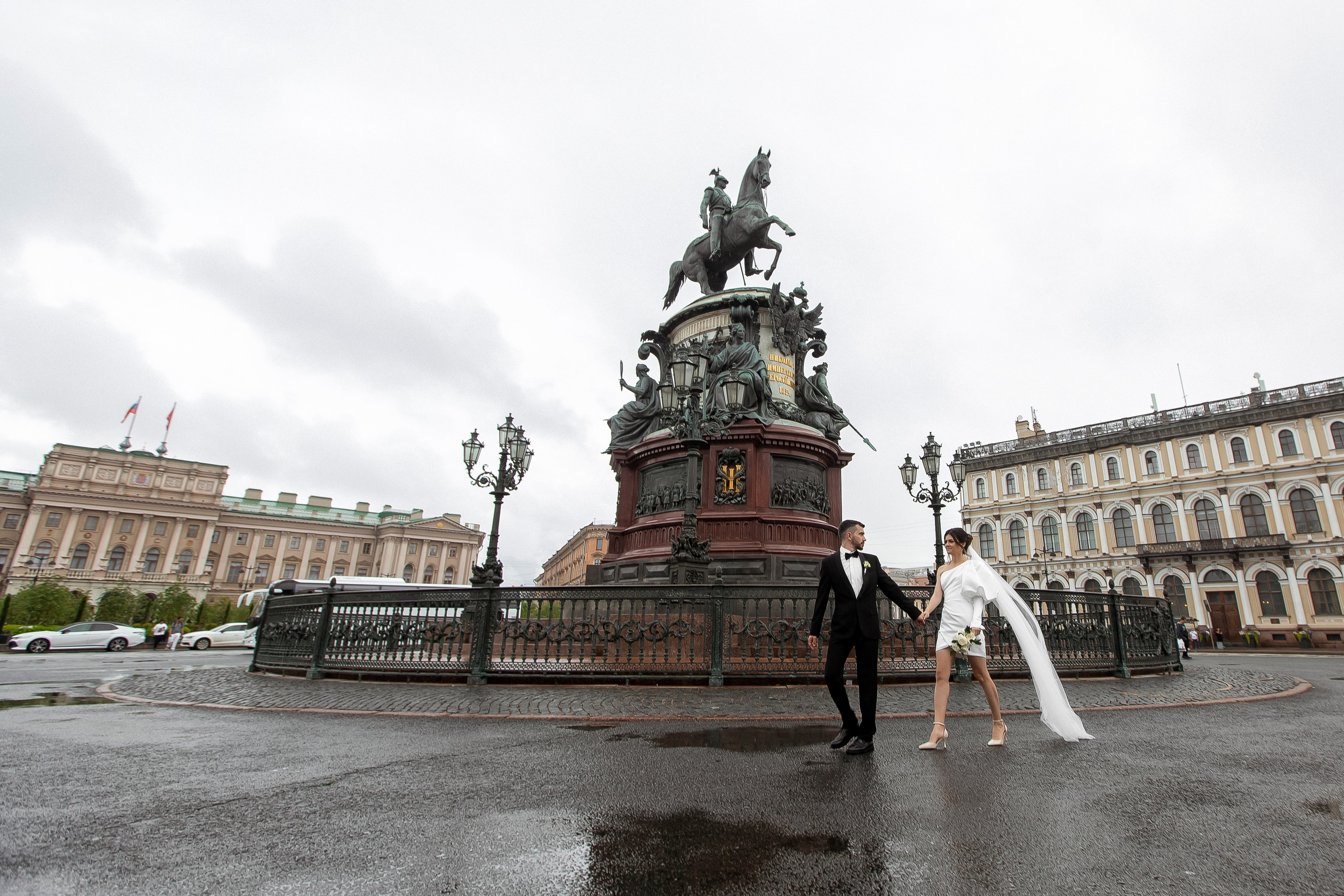 Жених и невеста идут по Исаакиевской площади в дождливую погоду