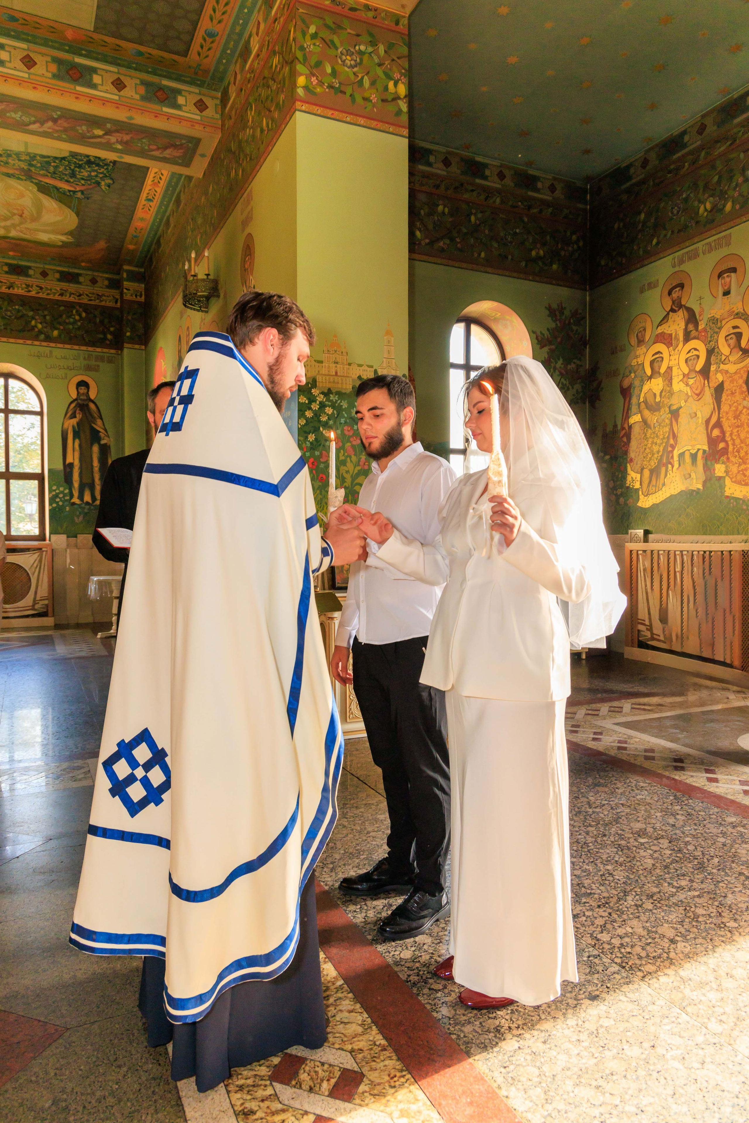 Обряд обручения: священник надевает кольца жениху и невесте.