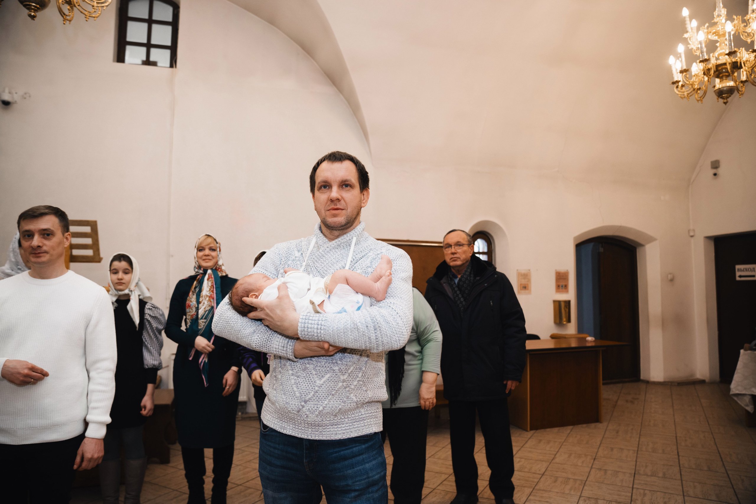 отец держит младенца в церкви