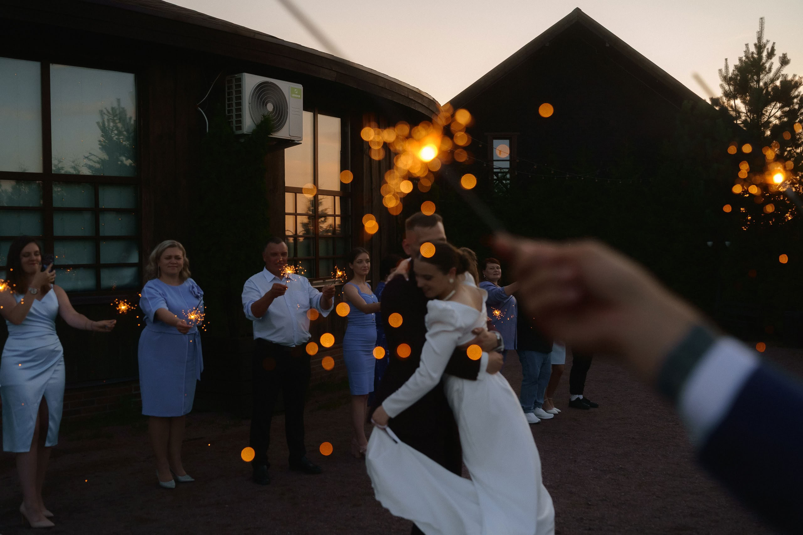 Гости и молодожёны с бенгальскими огнями у банкетного зала