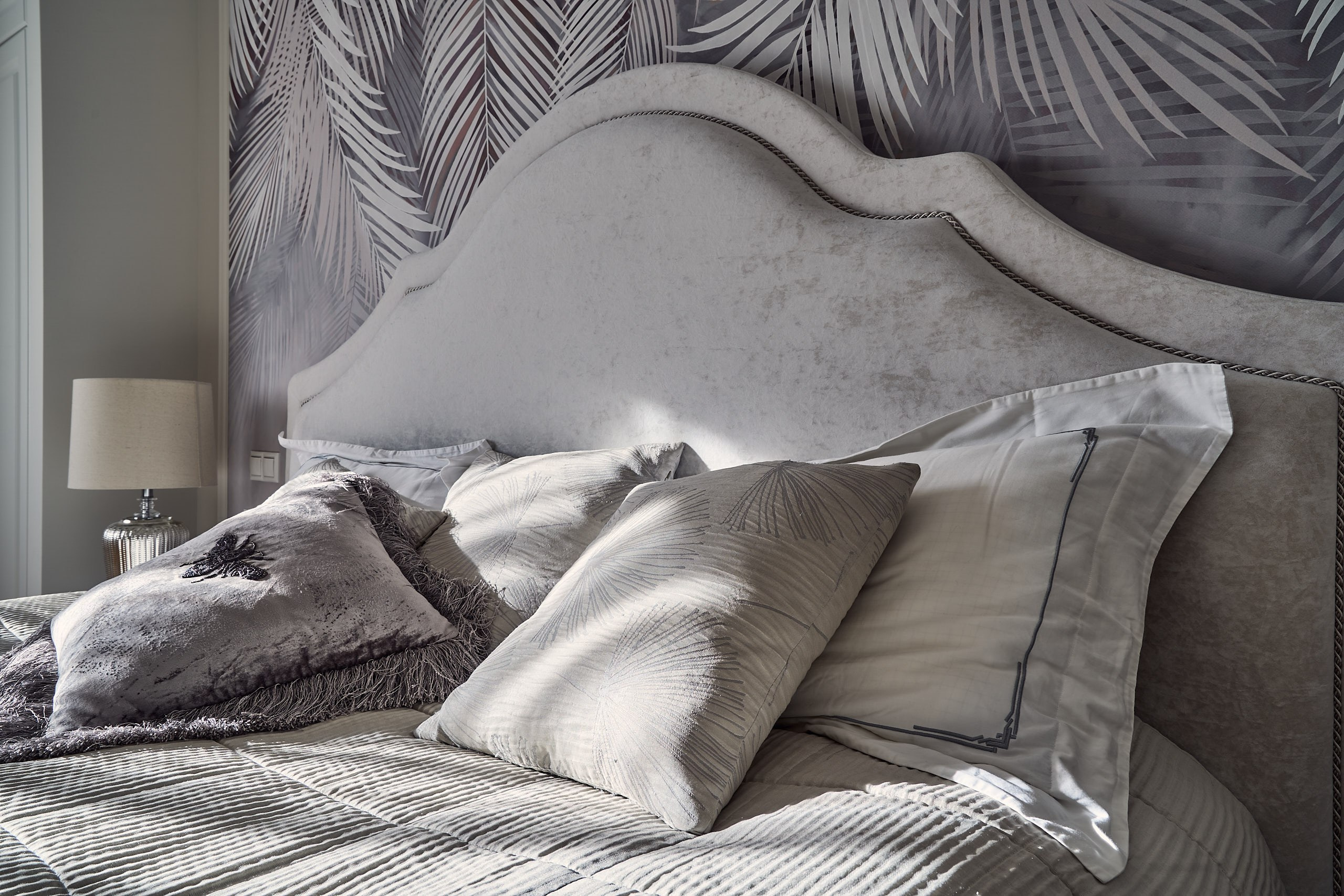 Интерьерная съемка в мастер-спальне, средний план с подушками, покрытыми пятнами предзакатного солнца