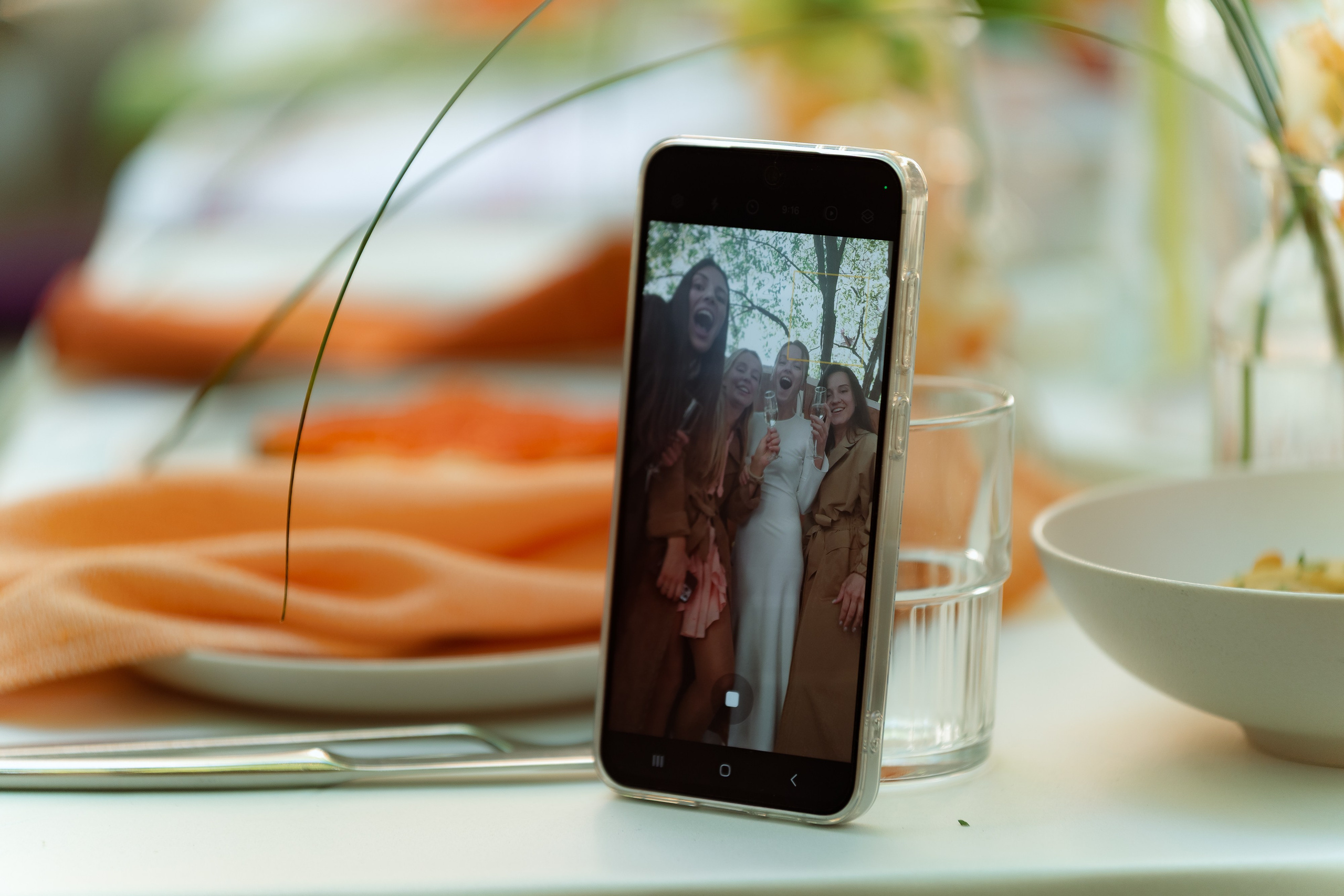 Смартфон на столе показывает фото пары, вокруг коралловые салфетки