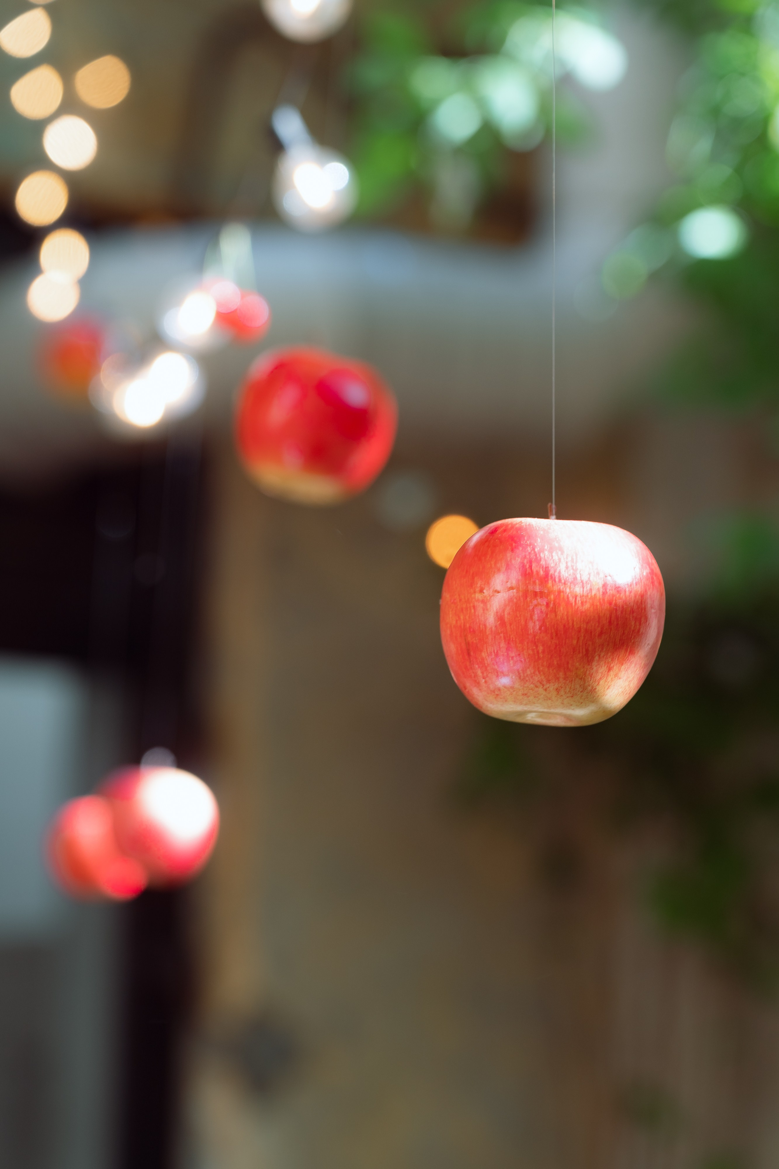 Красные яблоки зависли в воздухе на фоне гирлянд огоньков