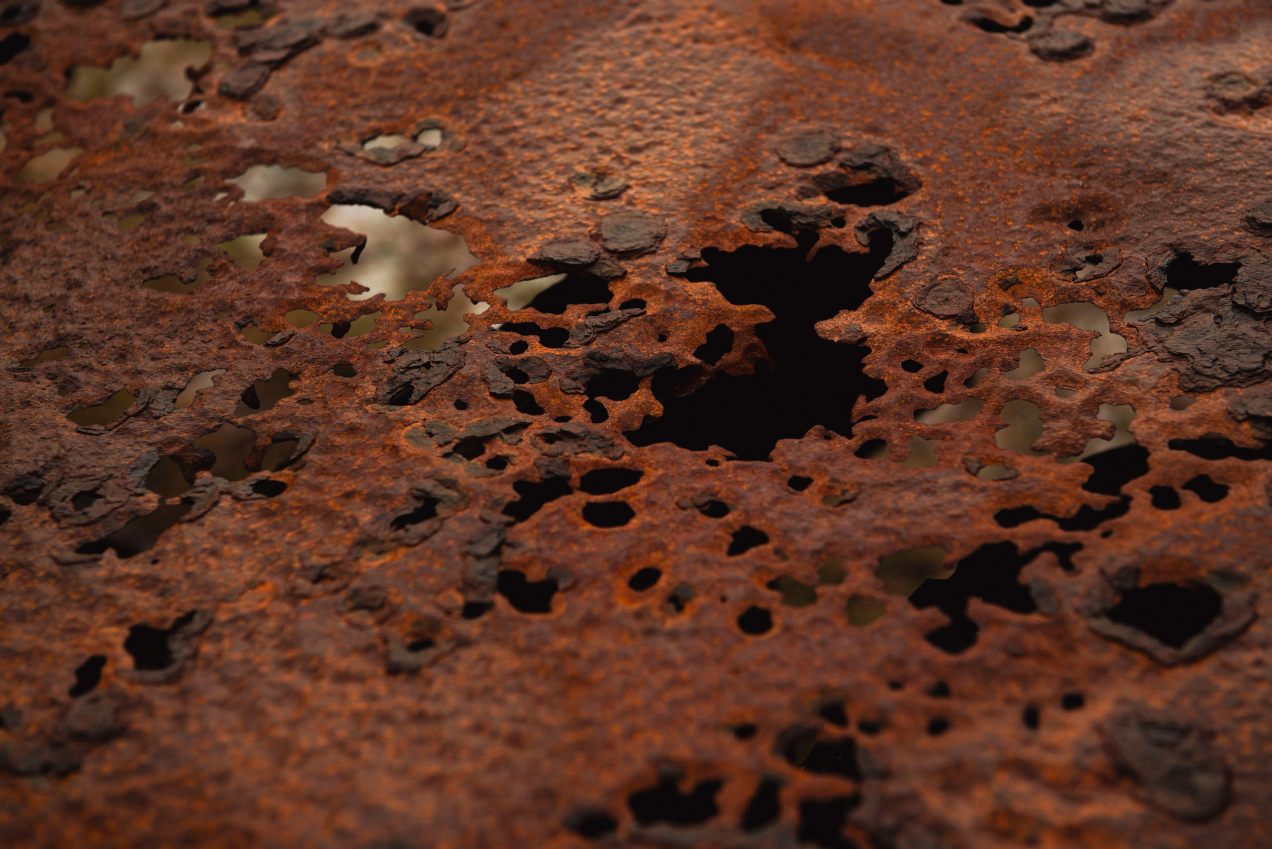 Крупный план текстуры сильно проржавевшего и корродированного металлического листа с многочисленными сквозными отверстиями.