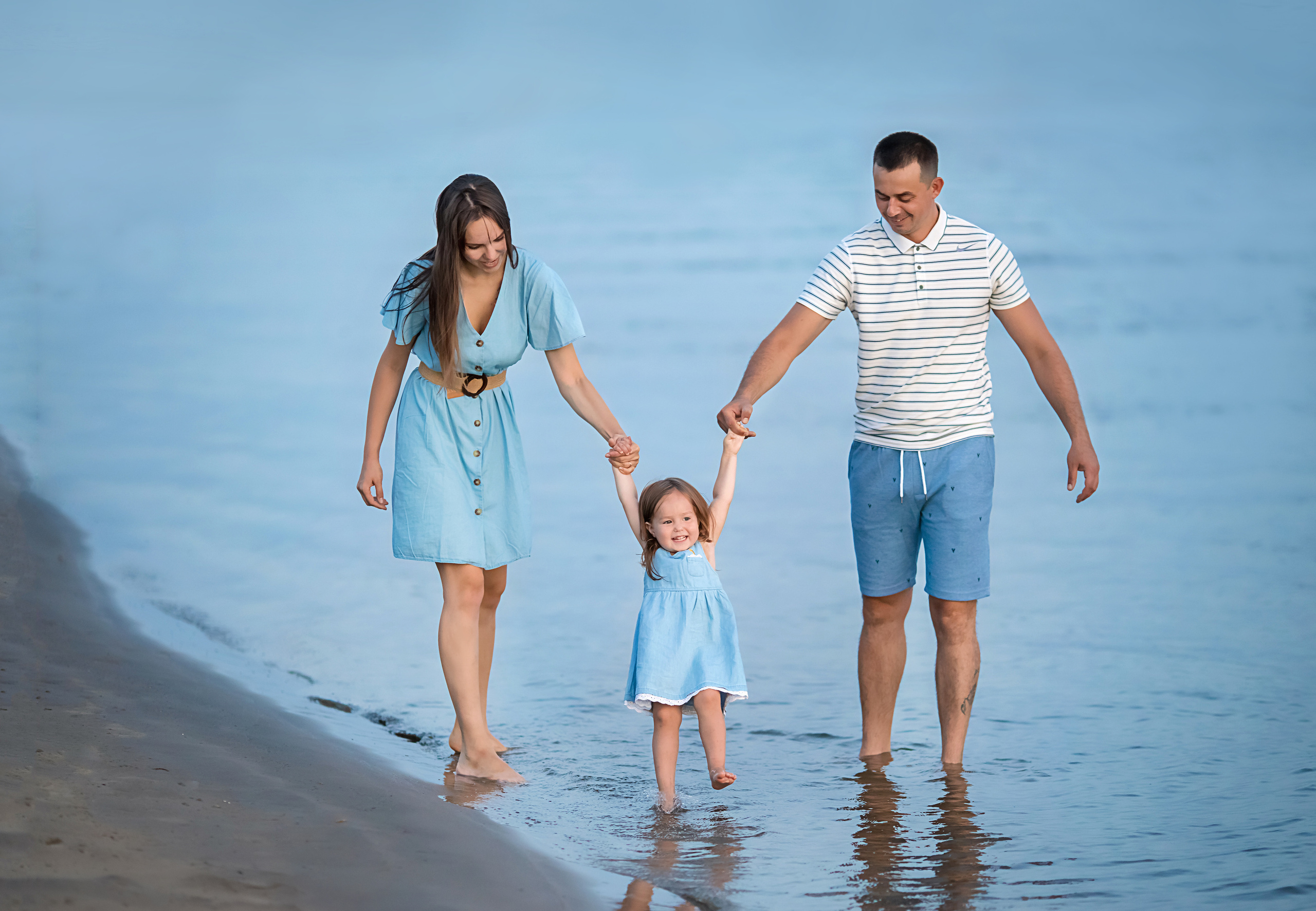 семья в закате гуляет вдоль реки