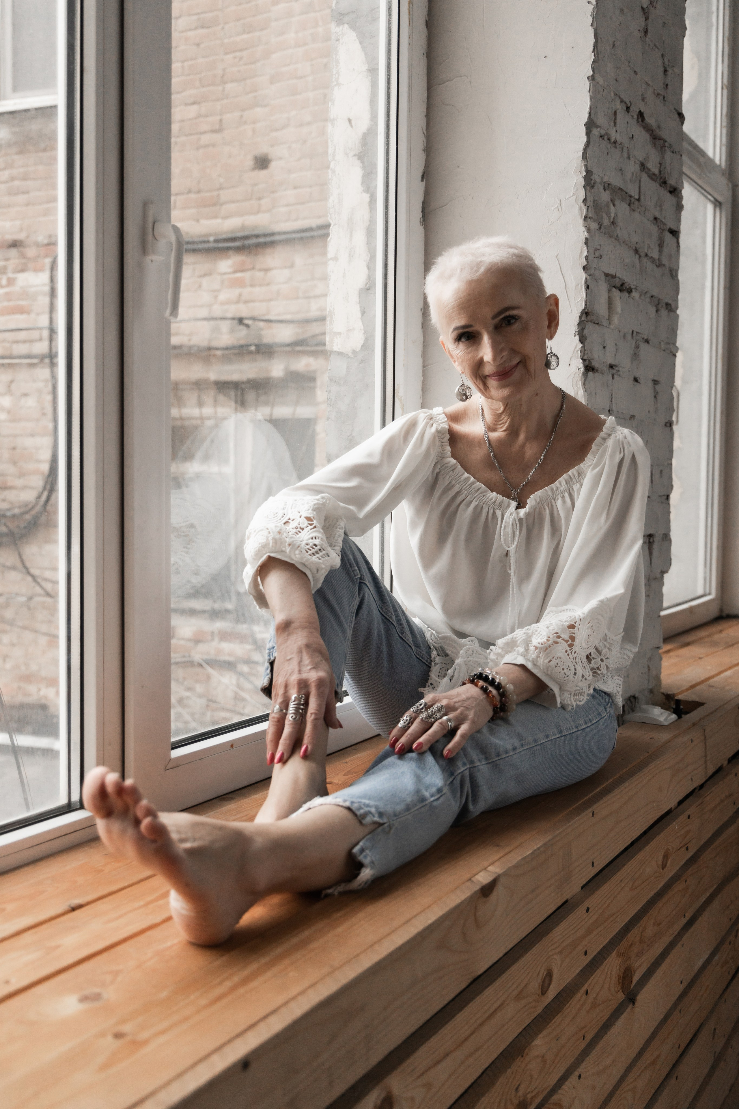 Красивая возрастная женщина, в белой блузке. Сидит на подоконнике. Студийная съёмка Астрахань.