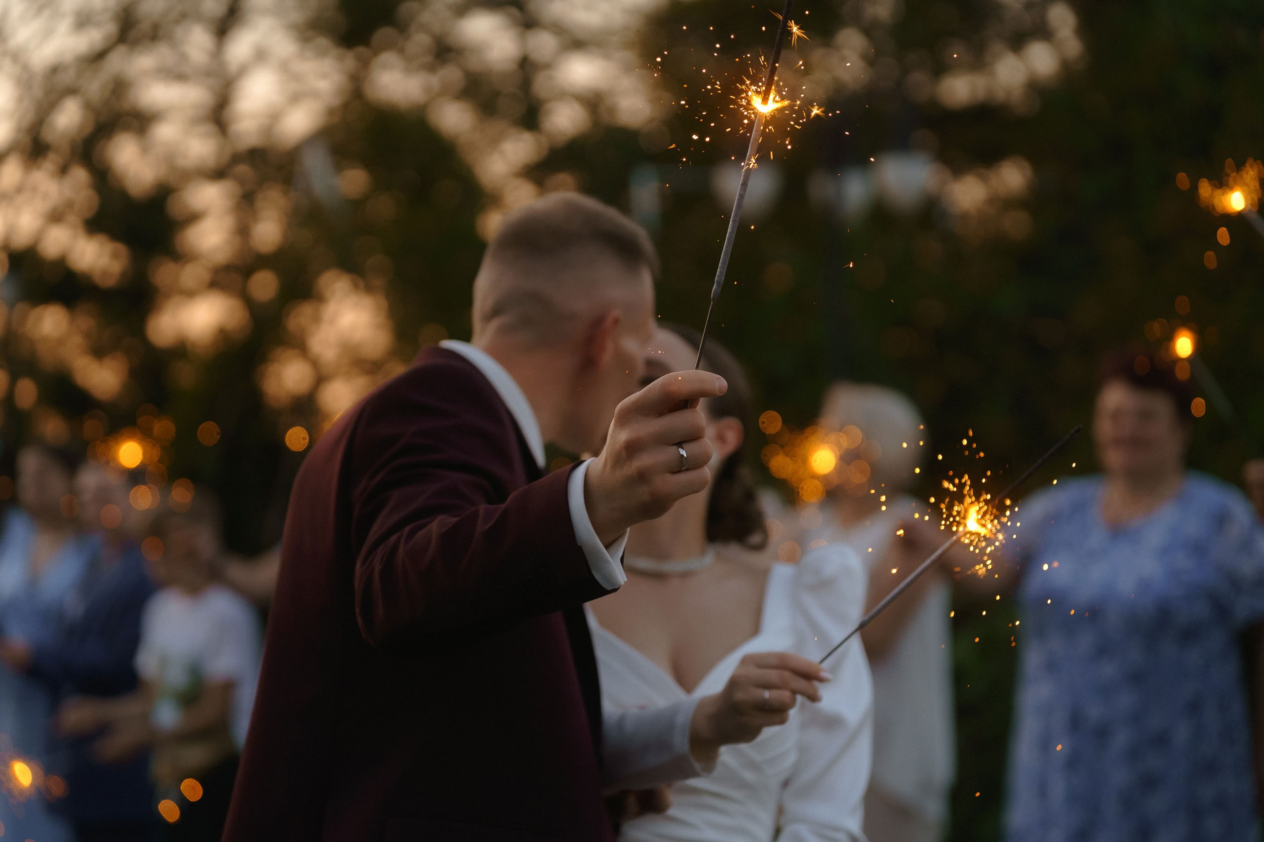 Поцелуй жениха и невесты с бенгальскими огнями на закате