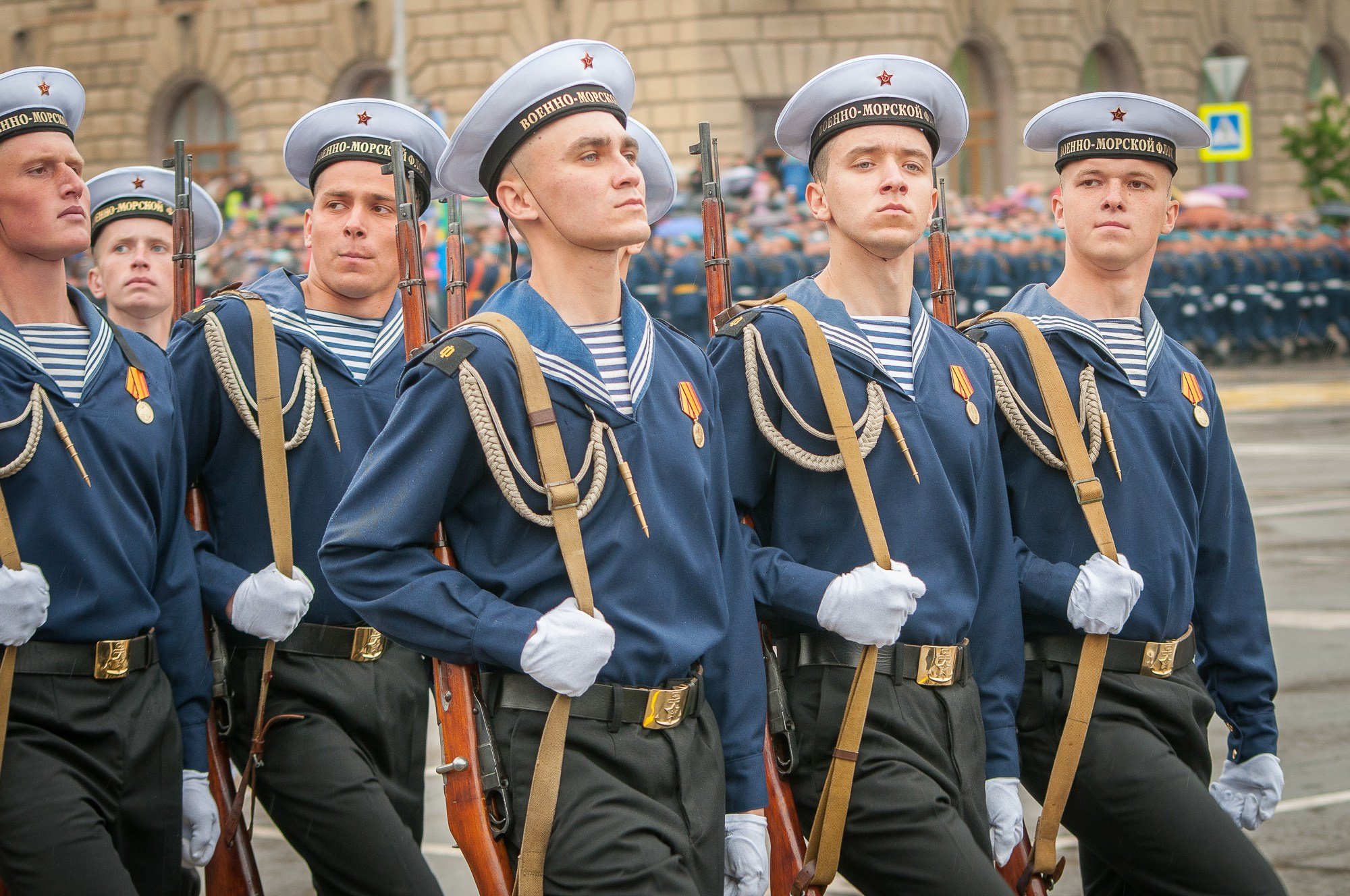 Моряки военно-морского флота идут на параде в тельняшках и бескозырках