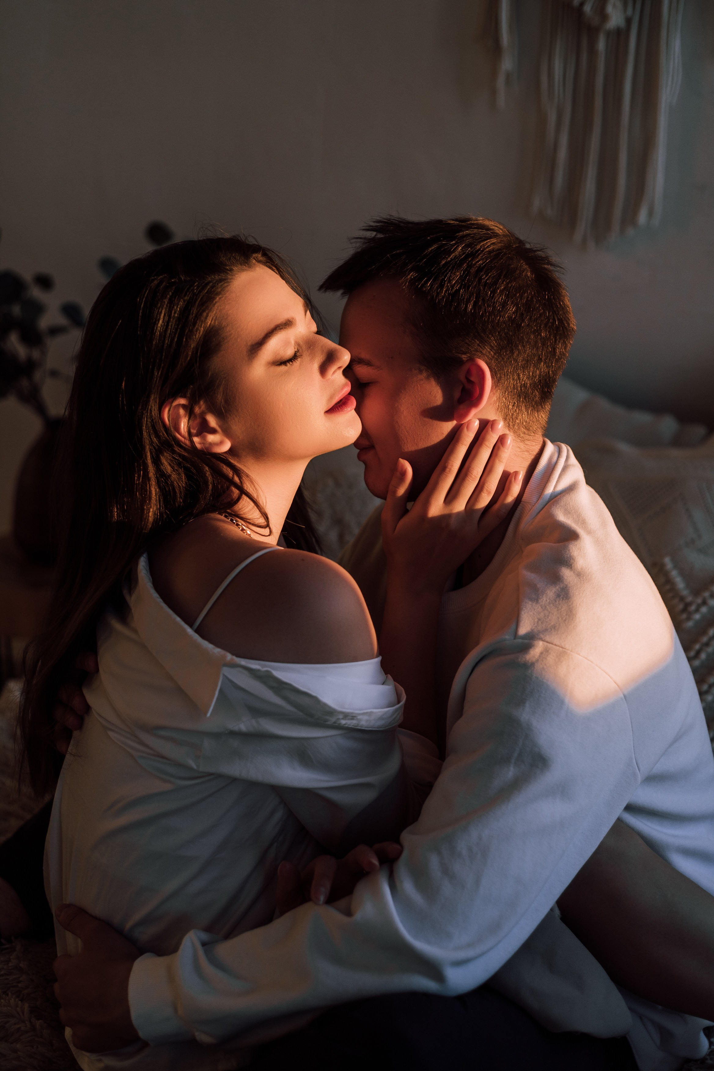 Пара обнимается на кровати , на них падает луч закатного солнца