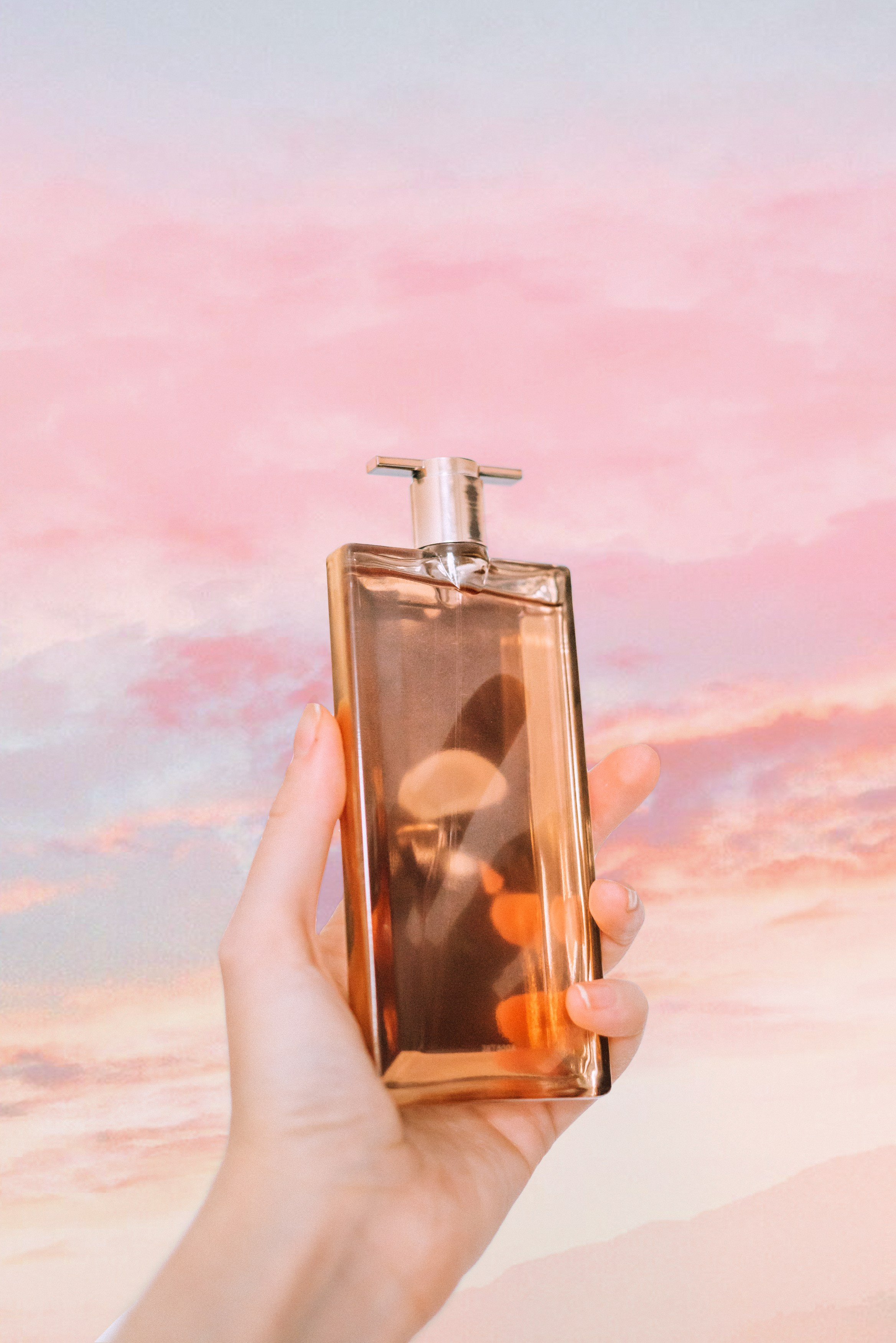 Парфюм в руках на фоне неба