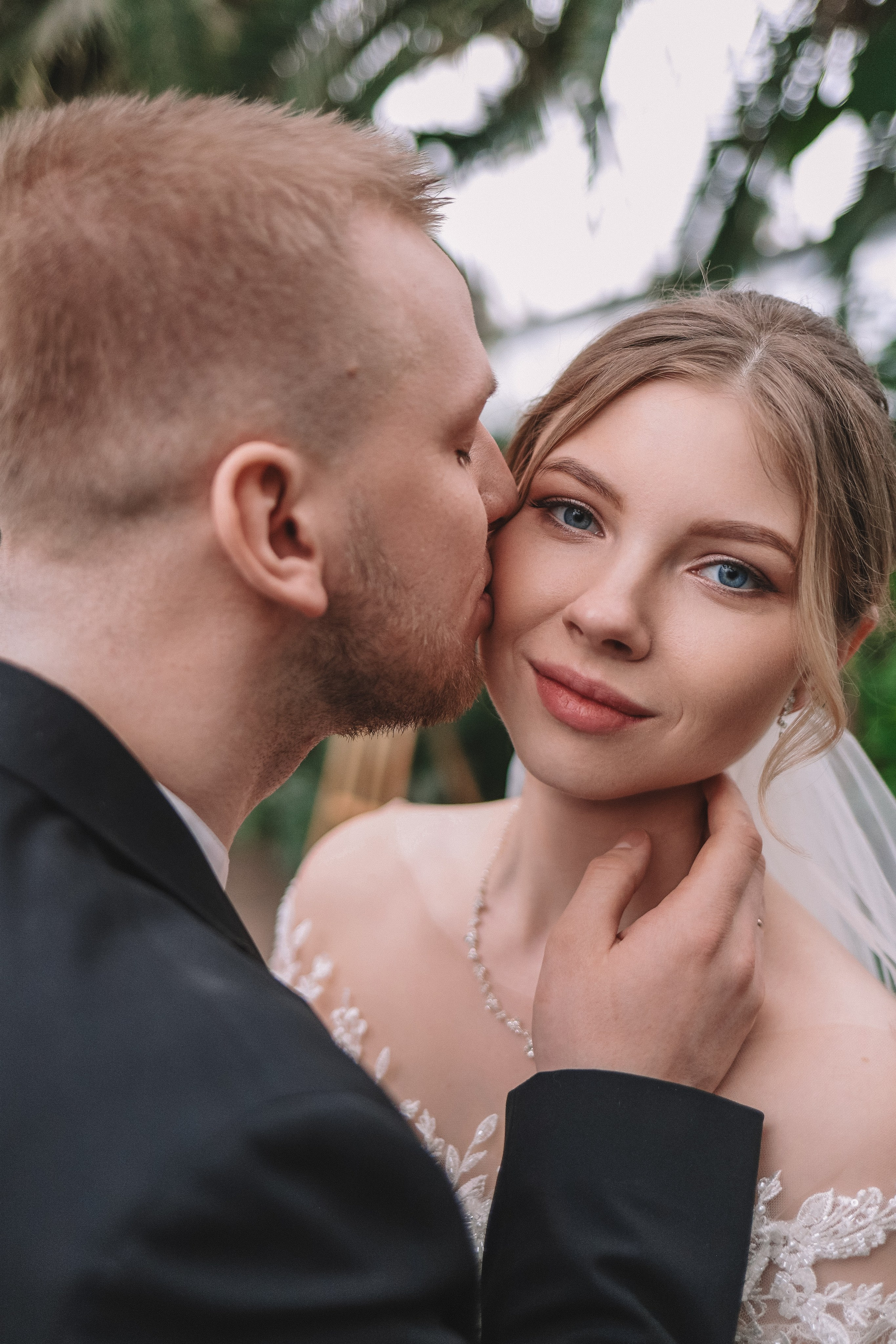 Портрет невесты и жениха, поцелуй, зелёный фон оранжереи