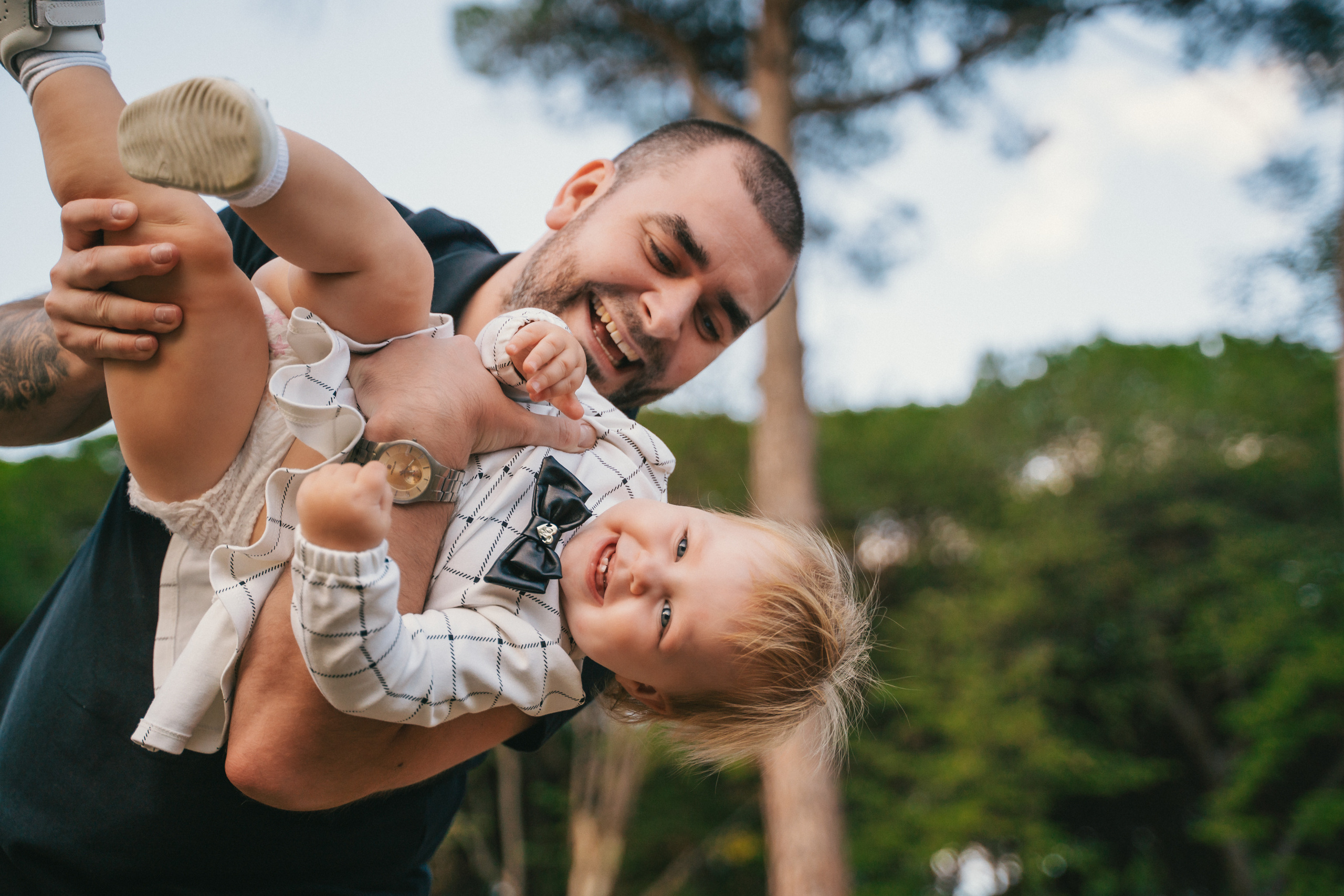 A child laughing and playing with their dad on a sunny day in a park in Montecatini, Tuscany