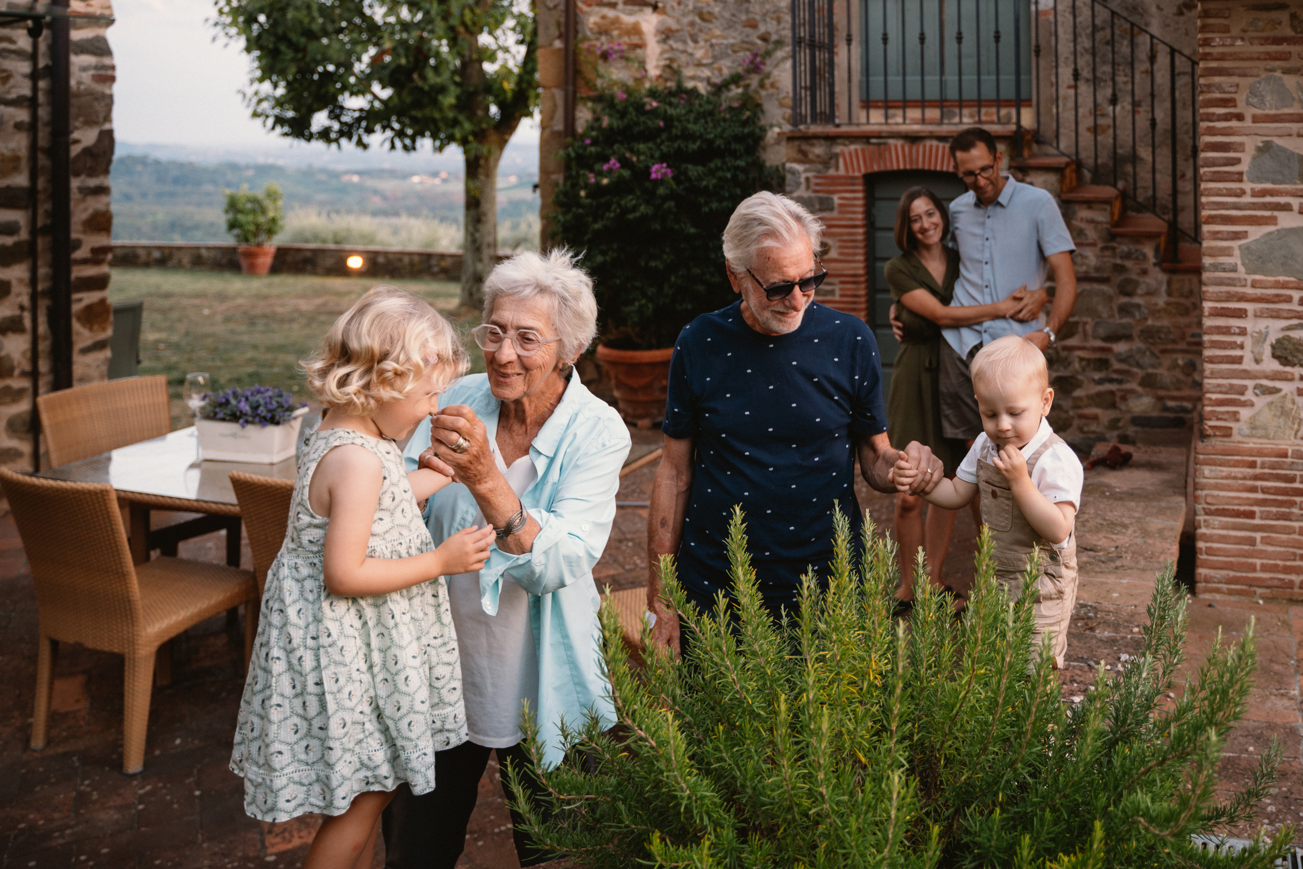 Parents and child walking together, silhouetted against the stunning colors of the setting sun in Tuscany.