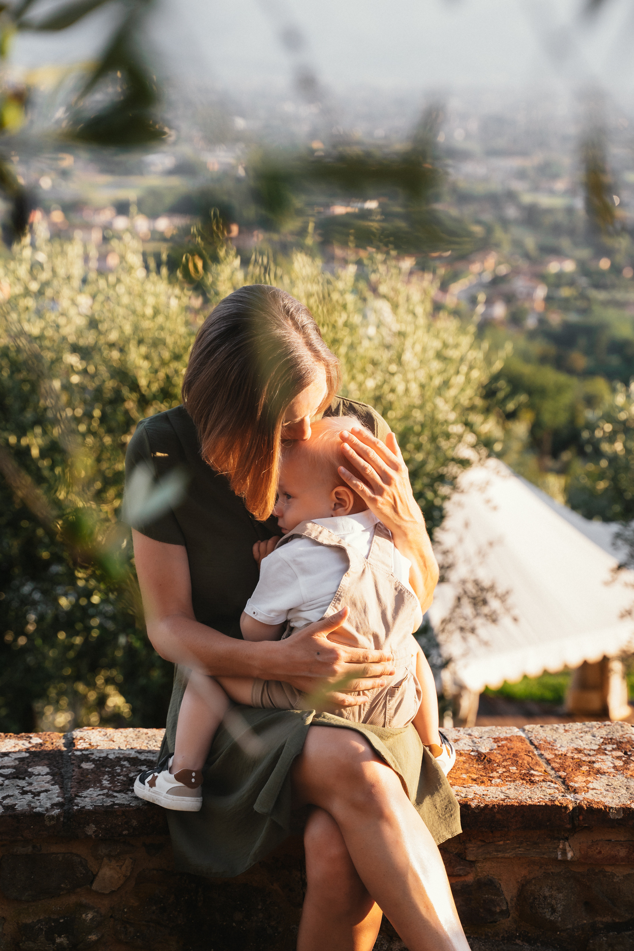 The family shares a picnic, with a rustic Tuscan landscape in the background