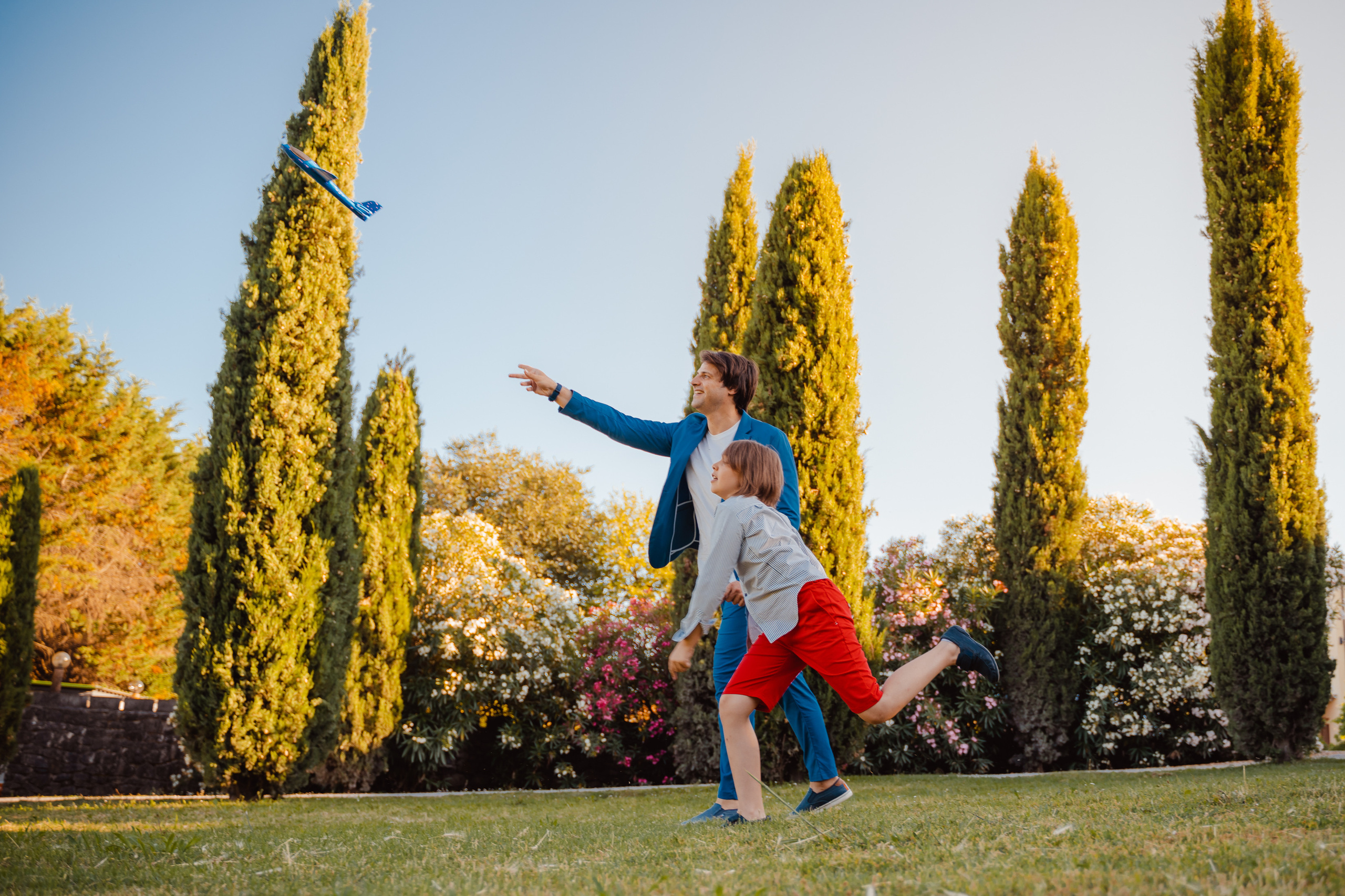 Kid plays with the airplane along a cypress-lined path