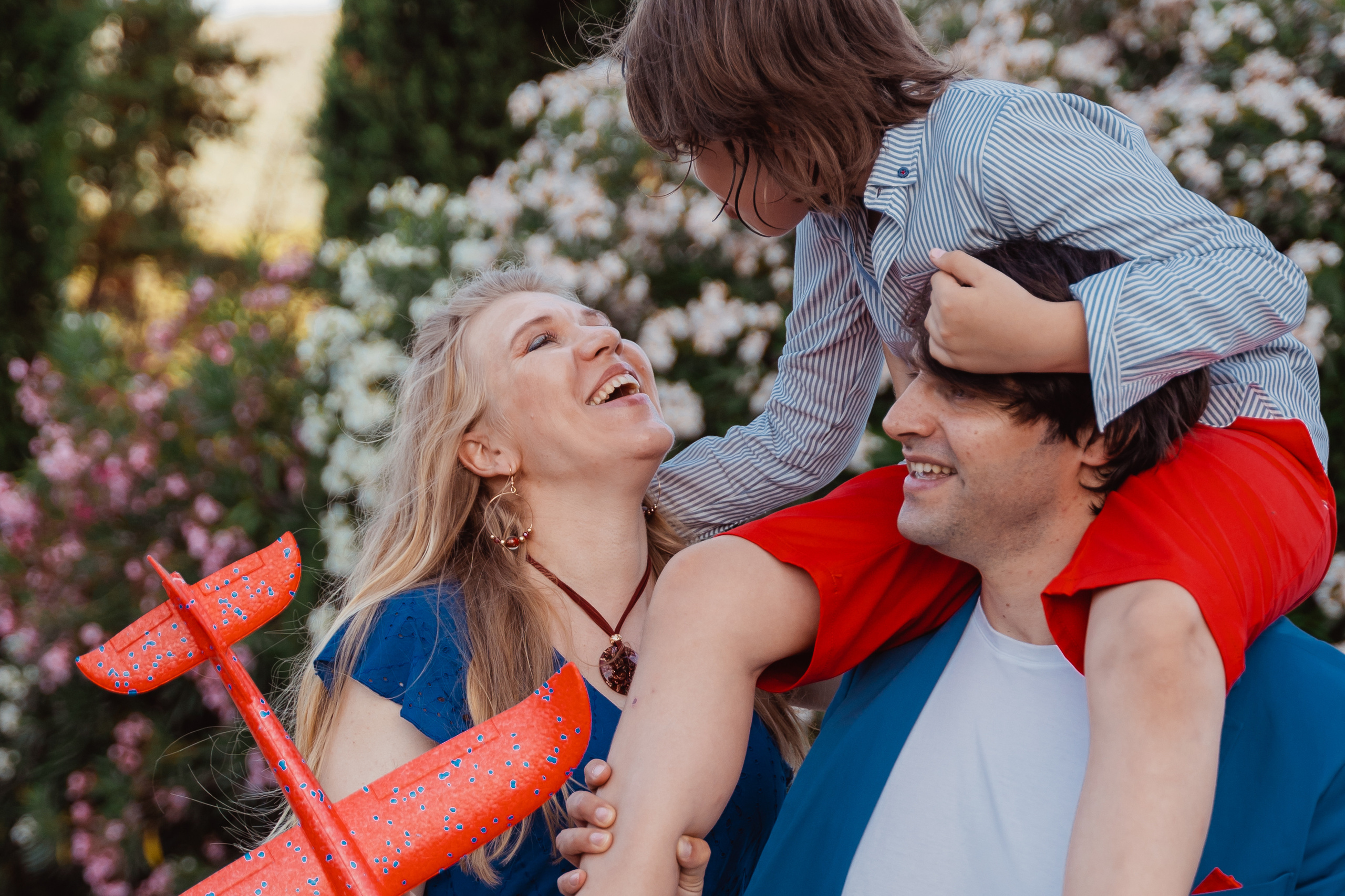 The family sharing a delightful moment while walking with their child framed by iconic Tuscan cypress trees.