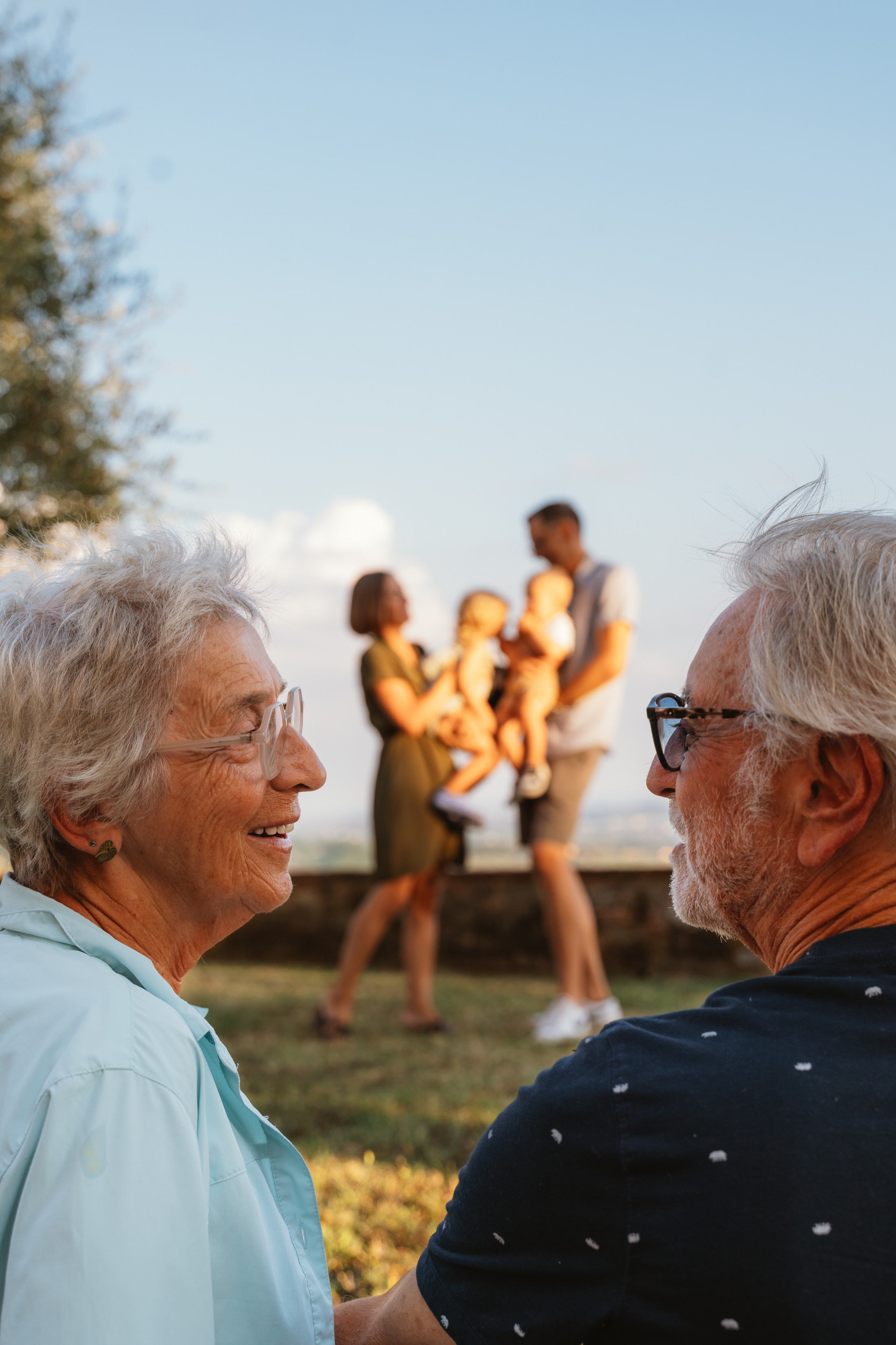The family takes a leisurely walk through the picturesque Tuscan countryside as the sun sets in the background.