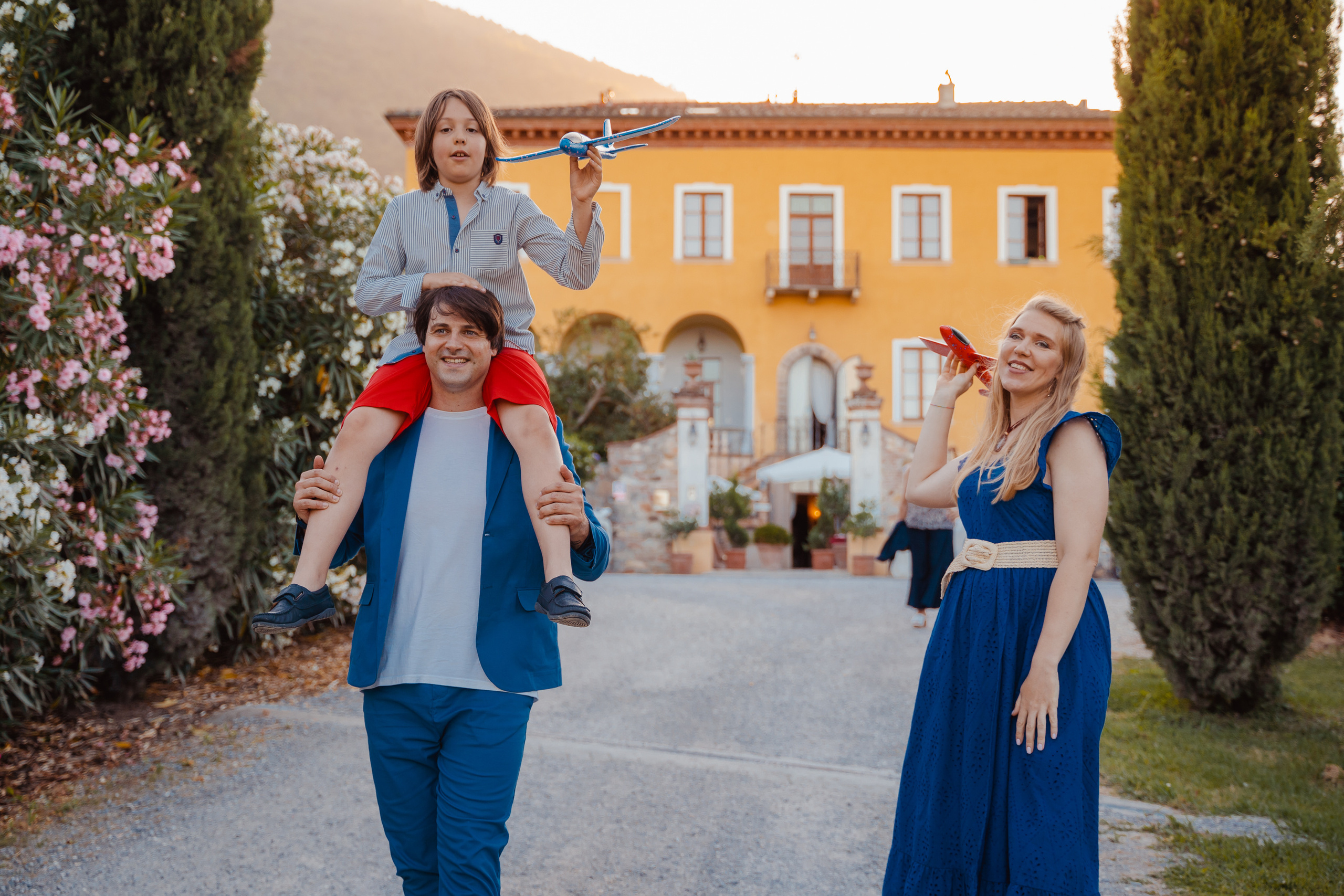 The family walks hand in hand along a cypress-lined path