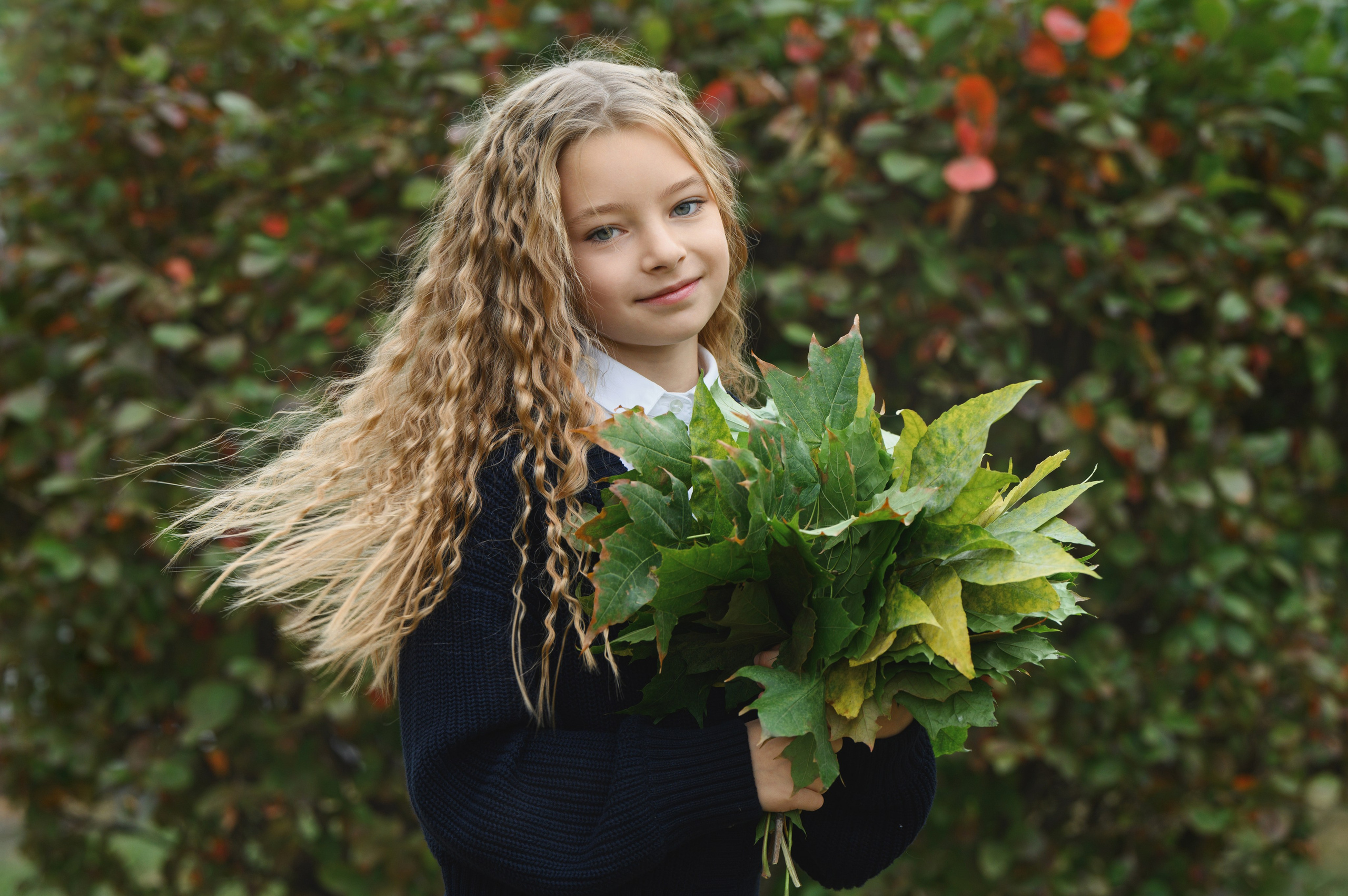 Портрет девочки с букетом зелёных листьев на улице