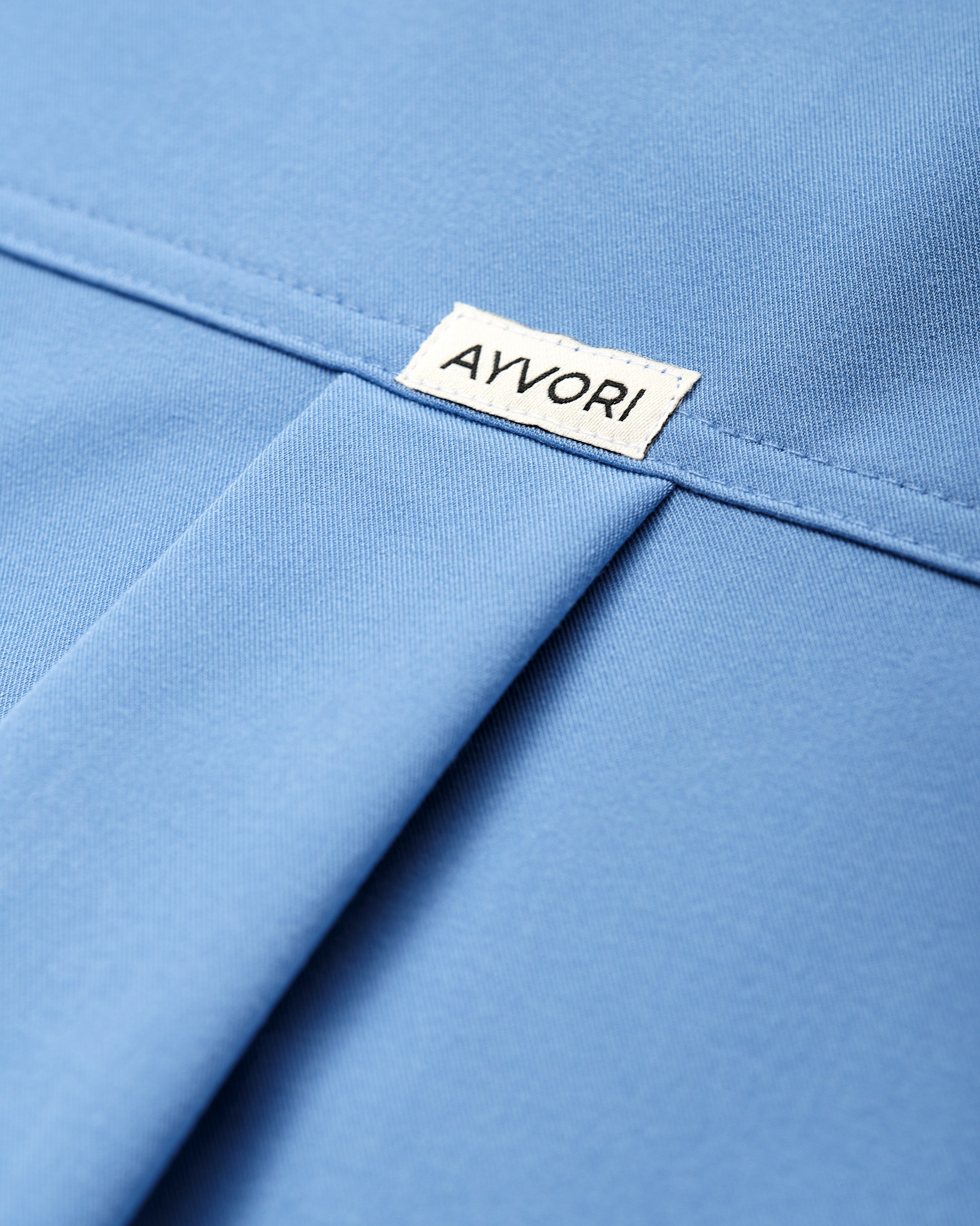 Крупный план ткани с логотипом AYVORI — предметная съёмка медицинской одежды с акцентом на детали
