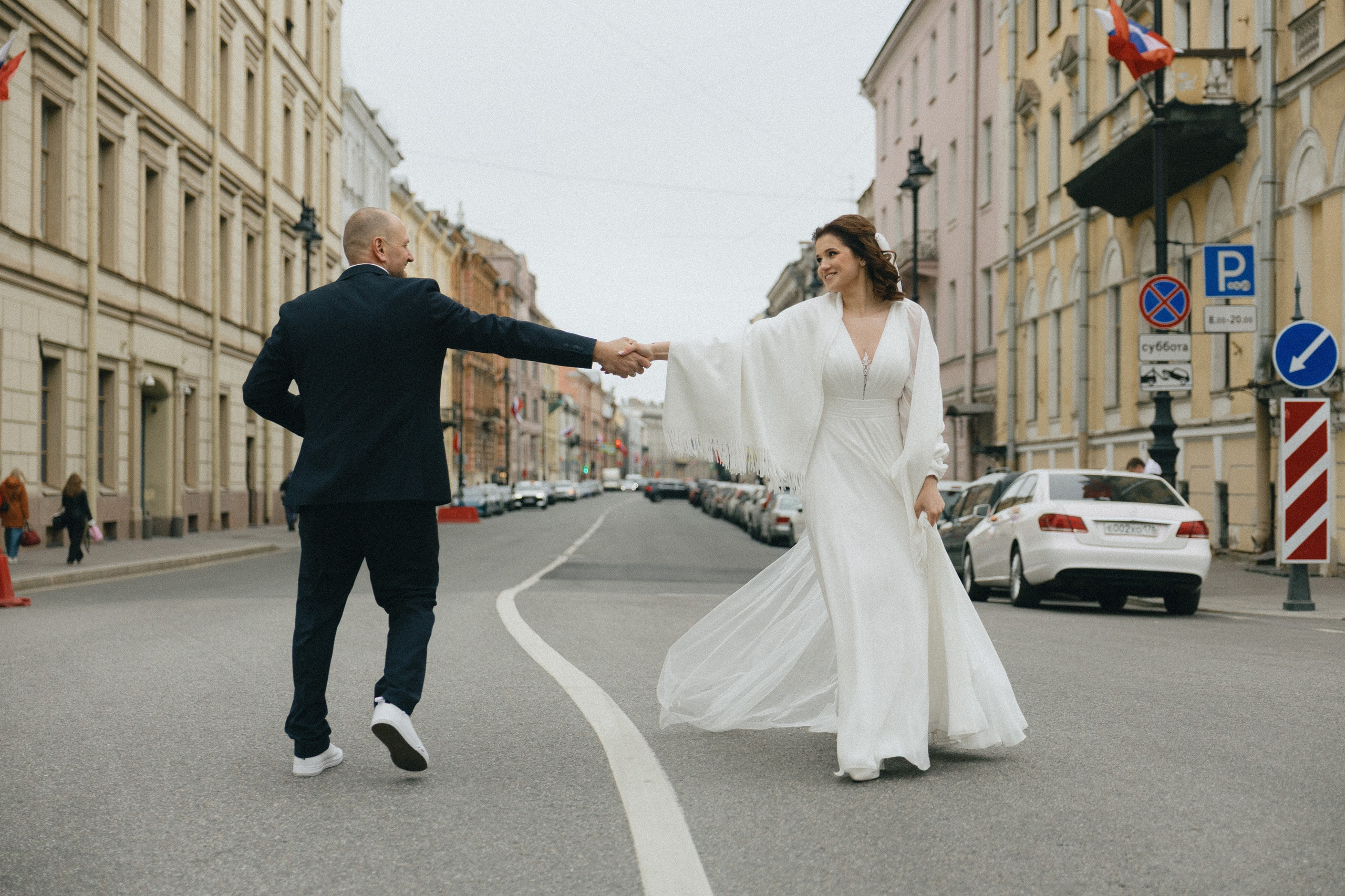 Динамичный кадр свадебной прогулки по улицам Санкт-Петербурга, жених и невеста в центре города.