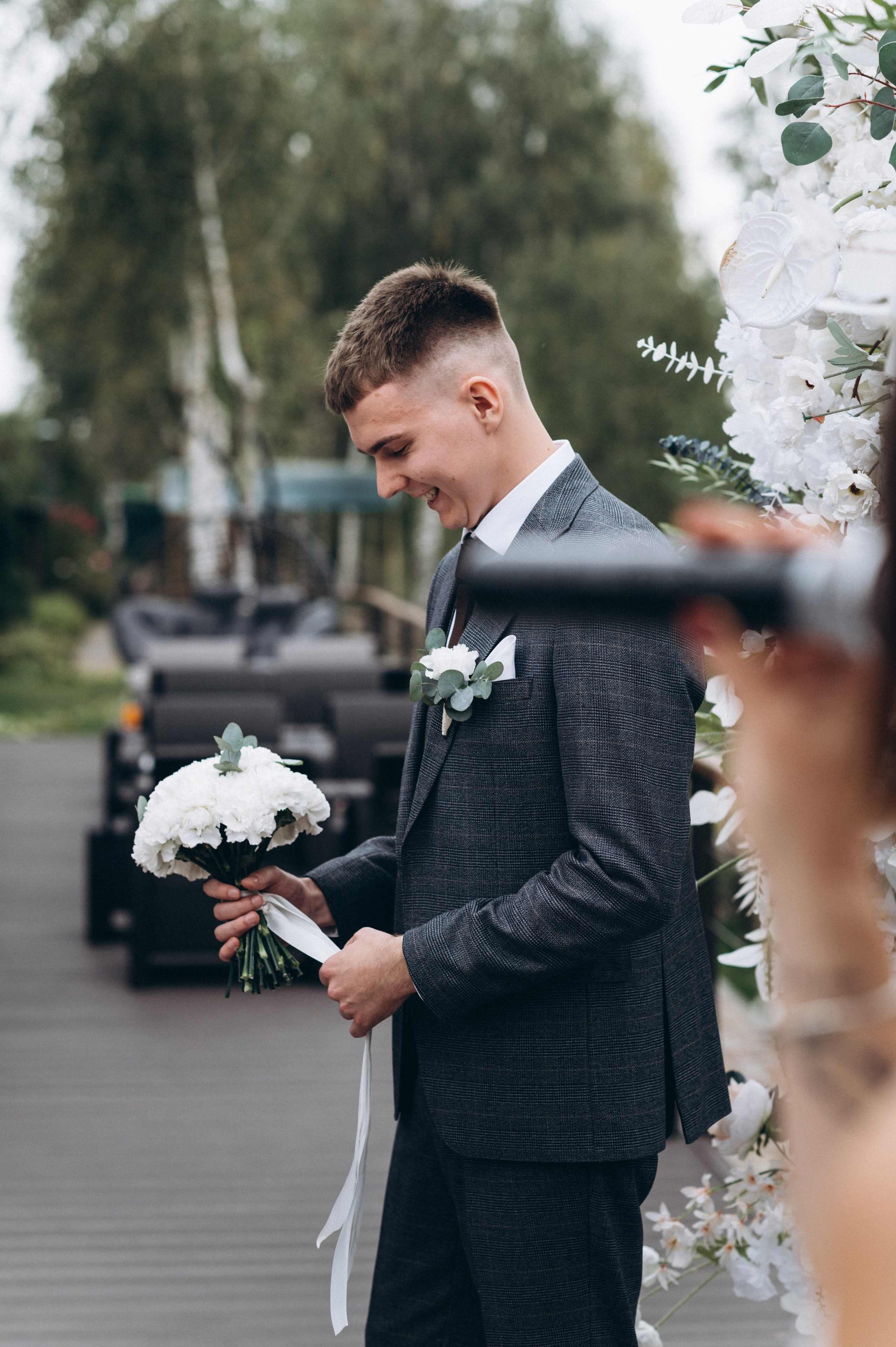 Жених держит свадебный букет перед выходом невесты