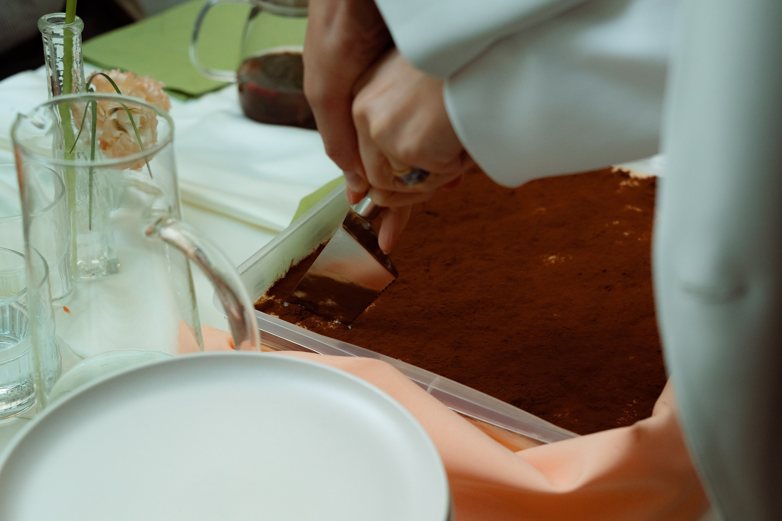 Нож разрезает пончик с глазурью на тарелке среди цветов