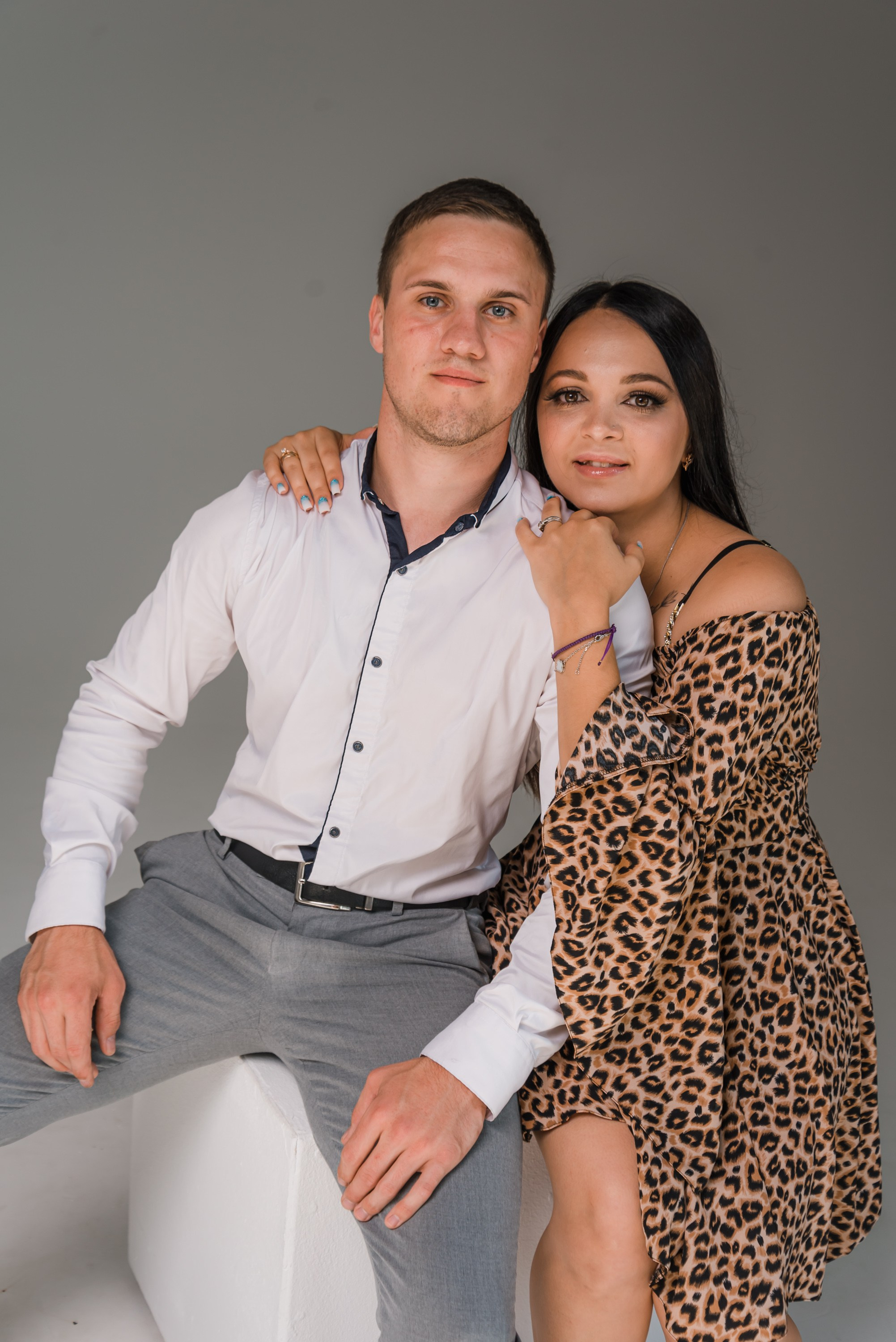 На фото муж и жена сидя на кубе в обнимку.