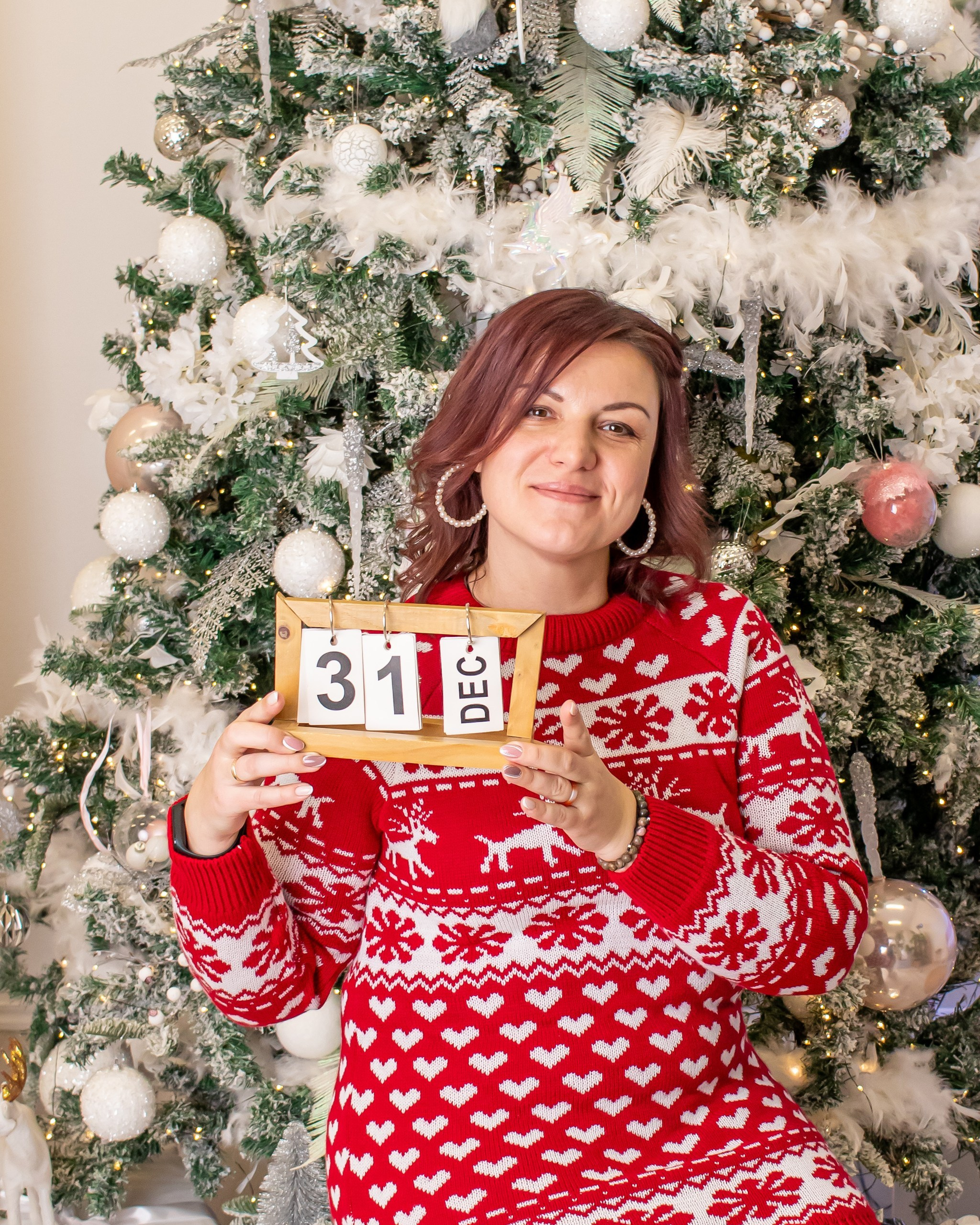 Портрет улыбающейся женщины в светлой новогодней студии с елкой и свечами, фотограф Карасёва Елена