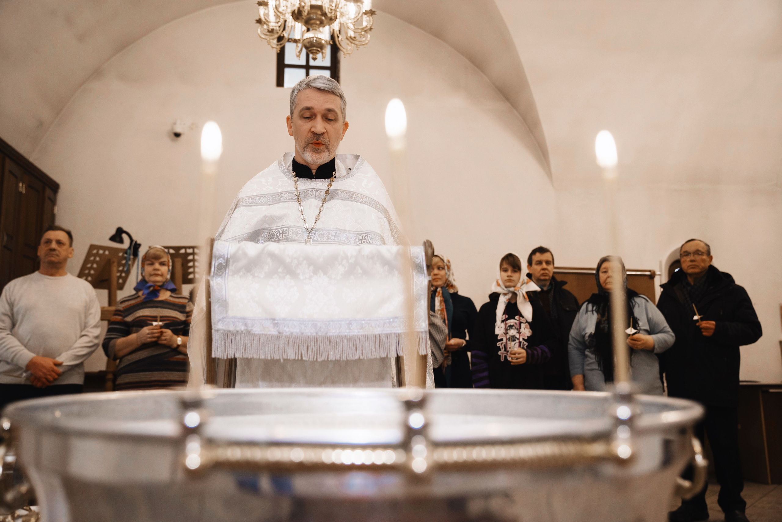 священник читает молитвы во время крещения ребенка
