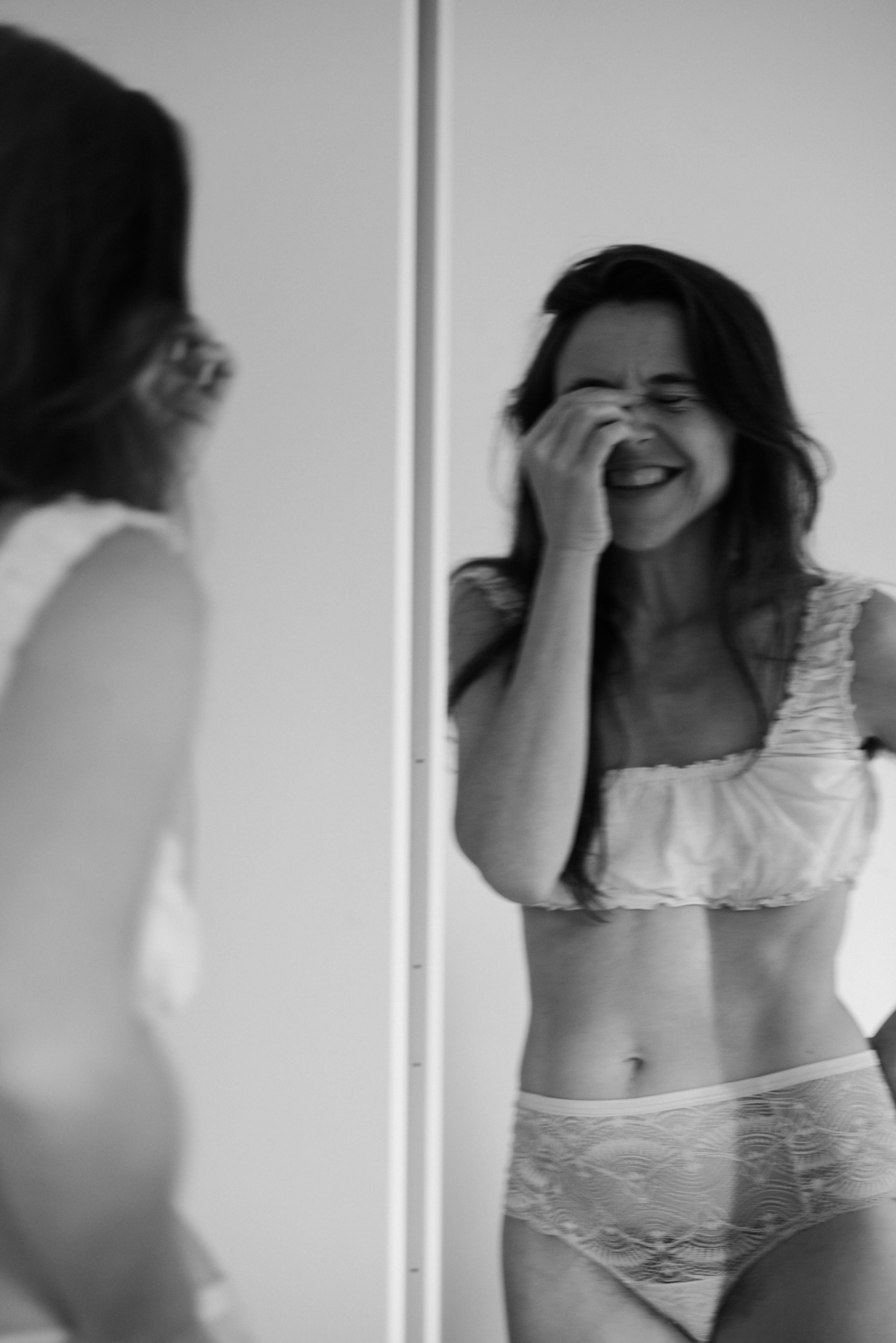 Boudoir portraits — woman in lingerie looking at her reflection in mirror, intimate and mindful moment.