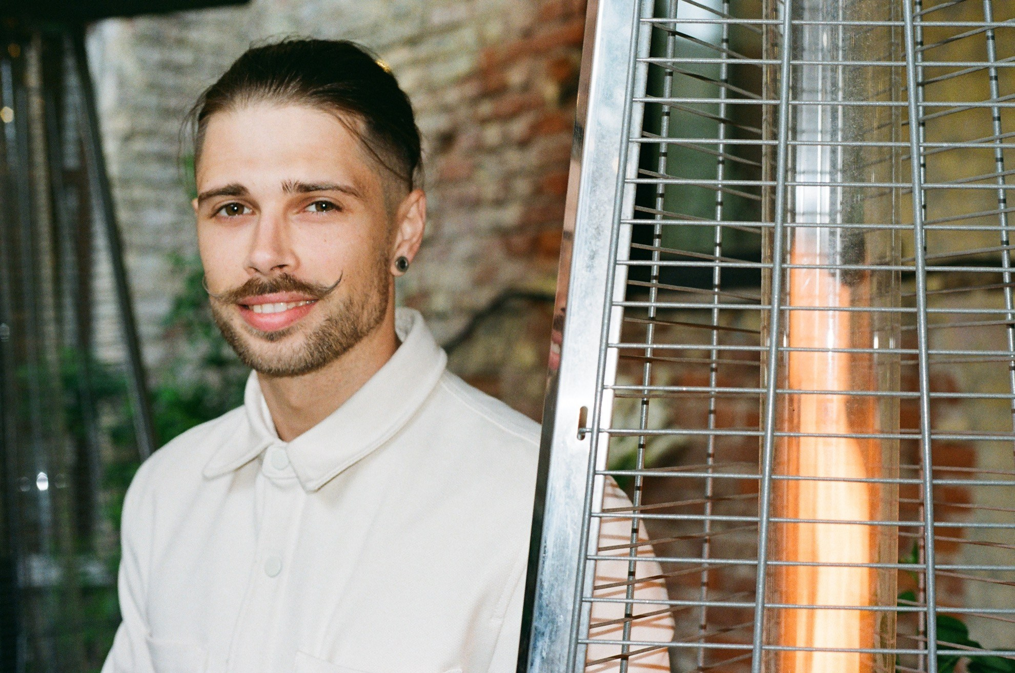 Портрет гостя в светлой рубашке у обогревателя, характерная плёночная зернистость