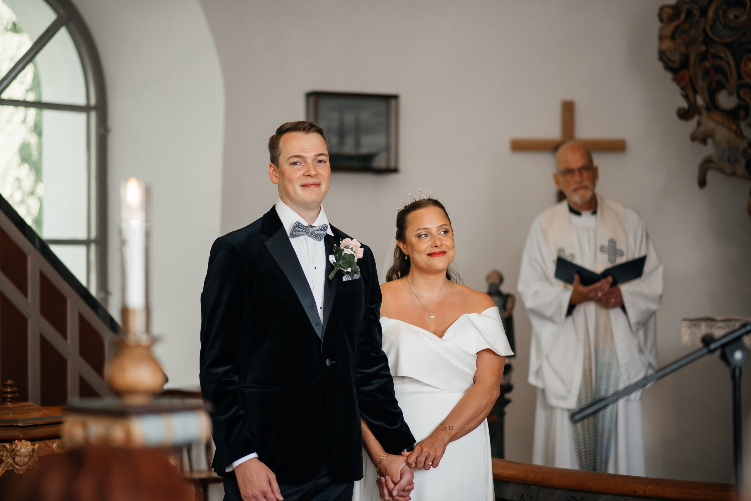 Bröllopsfotografering i kyrkan – detaljer från ceremonin med brud och brudgum i fokus. Wedding photography in church – ceremony details with bride and groom in focus.