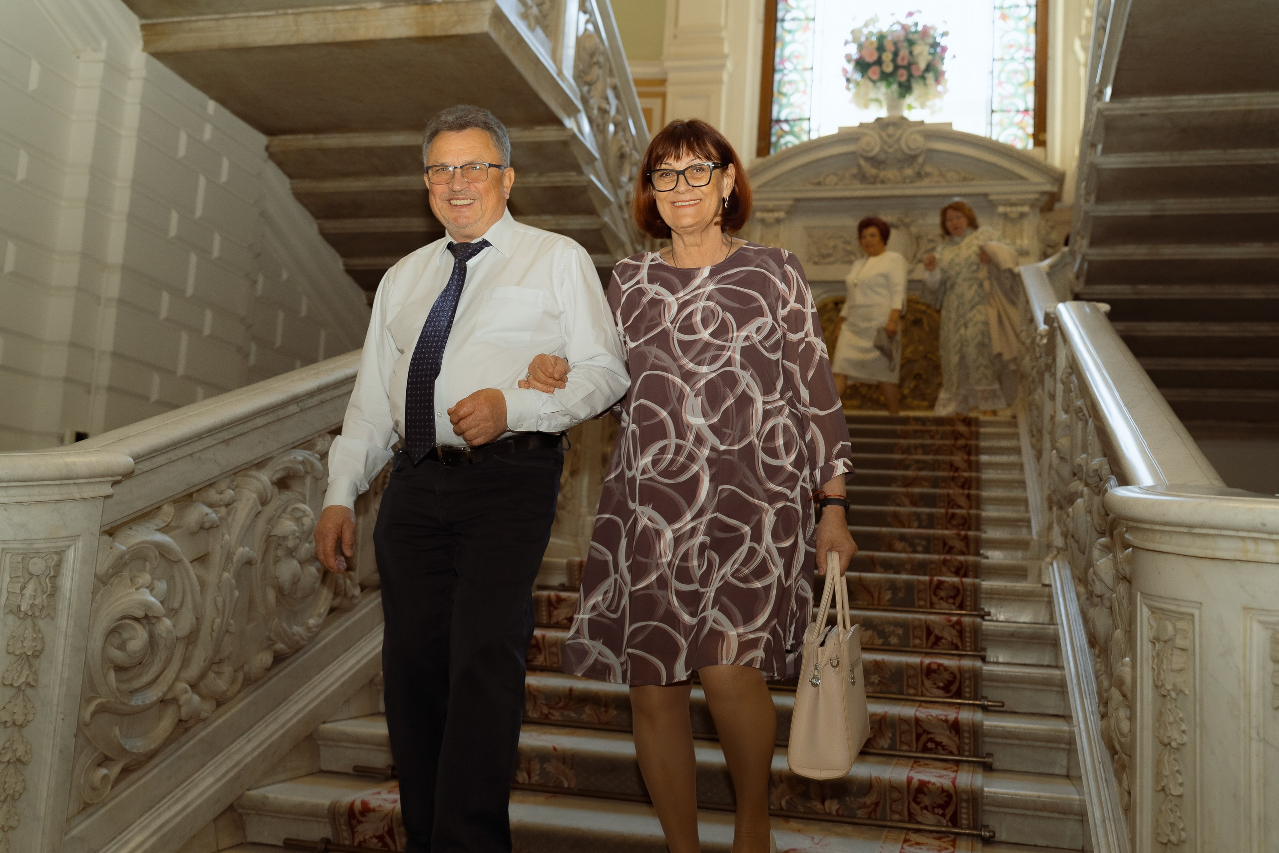 Родители следуют за молодожёнами по лестнице дворца бракосочетания