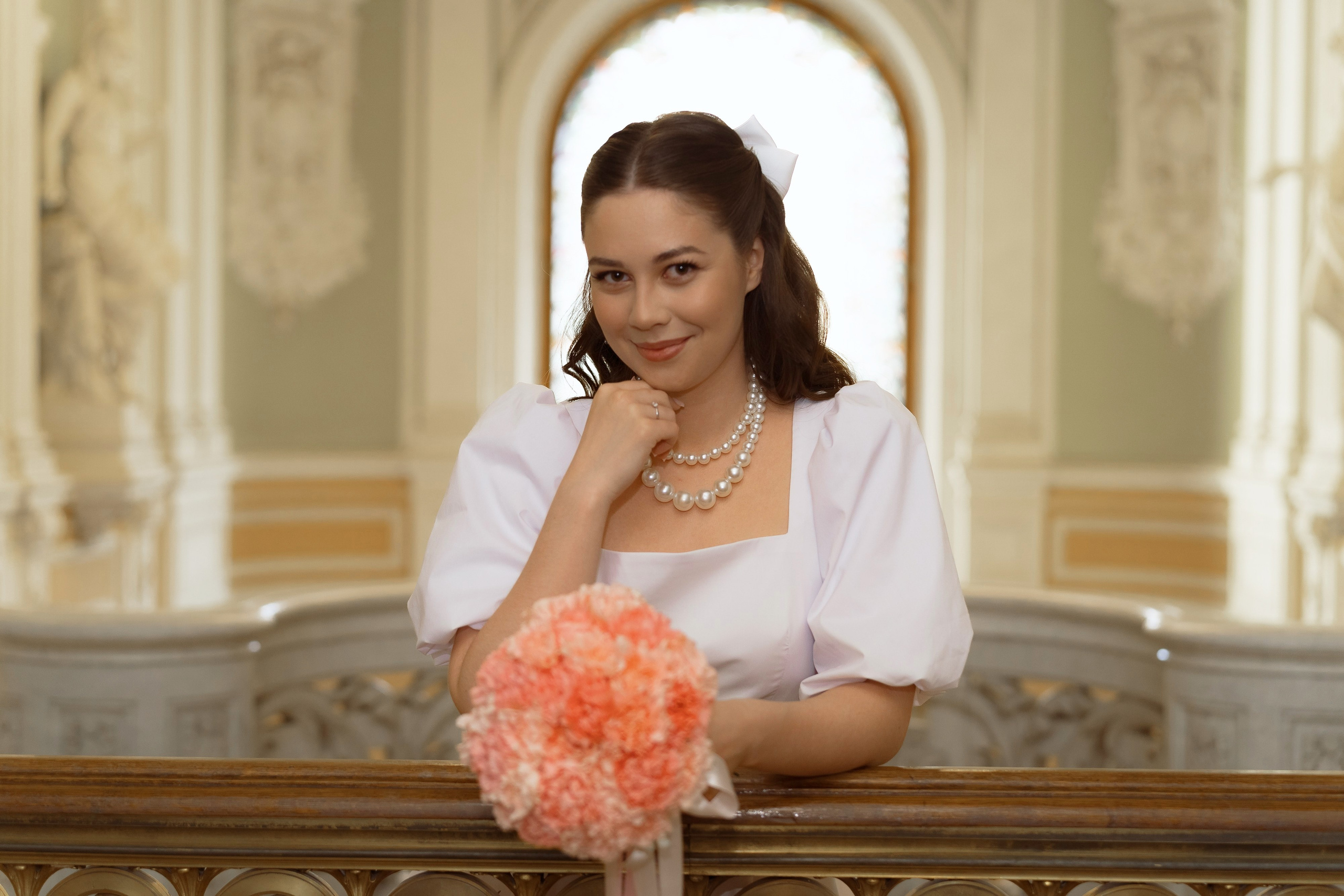 Невеста с букетом у окна в старинном дворце бракосочетания