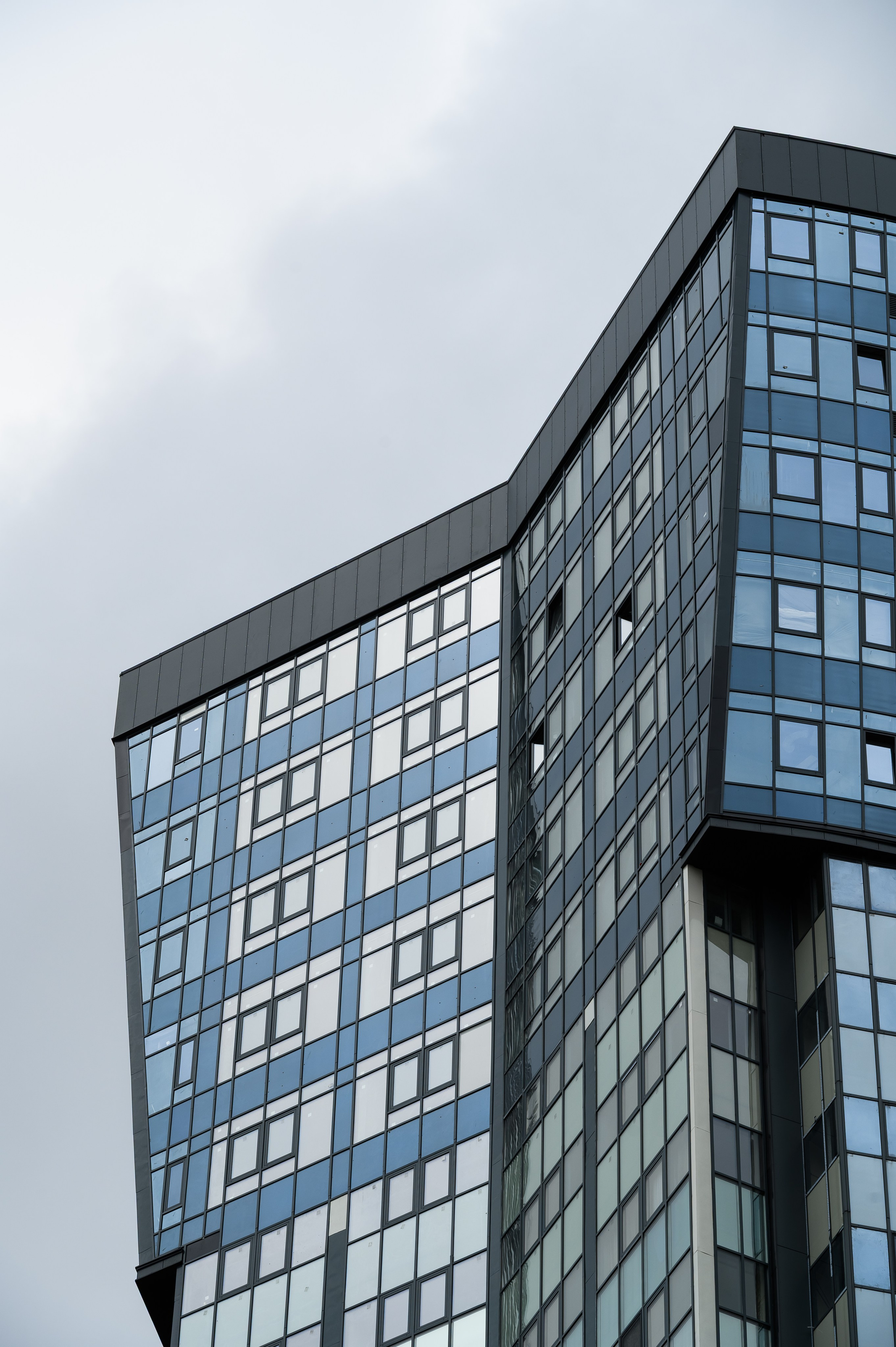 Вид сбоку жилого комплекса Авалон-Сити с отражениями неба в окнах и мягкими оттенками материалов